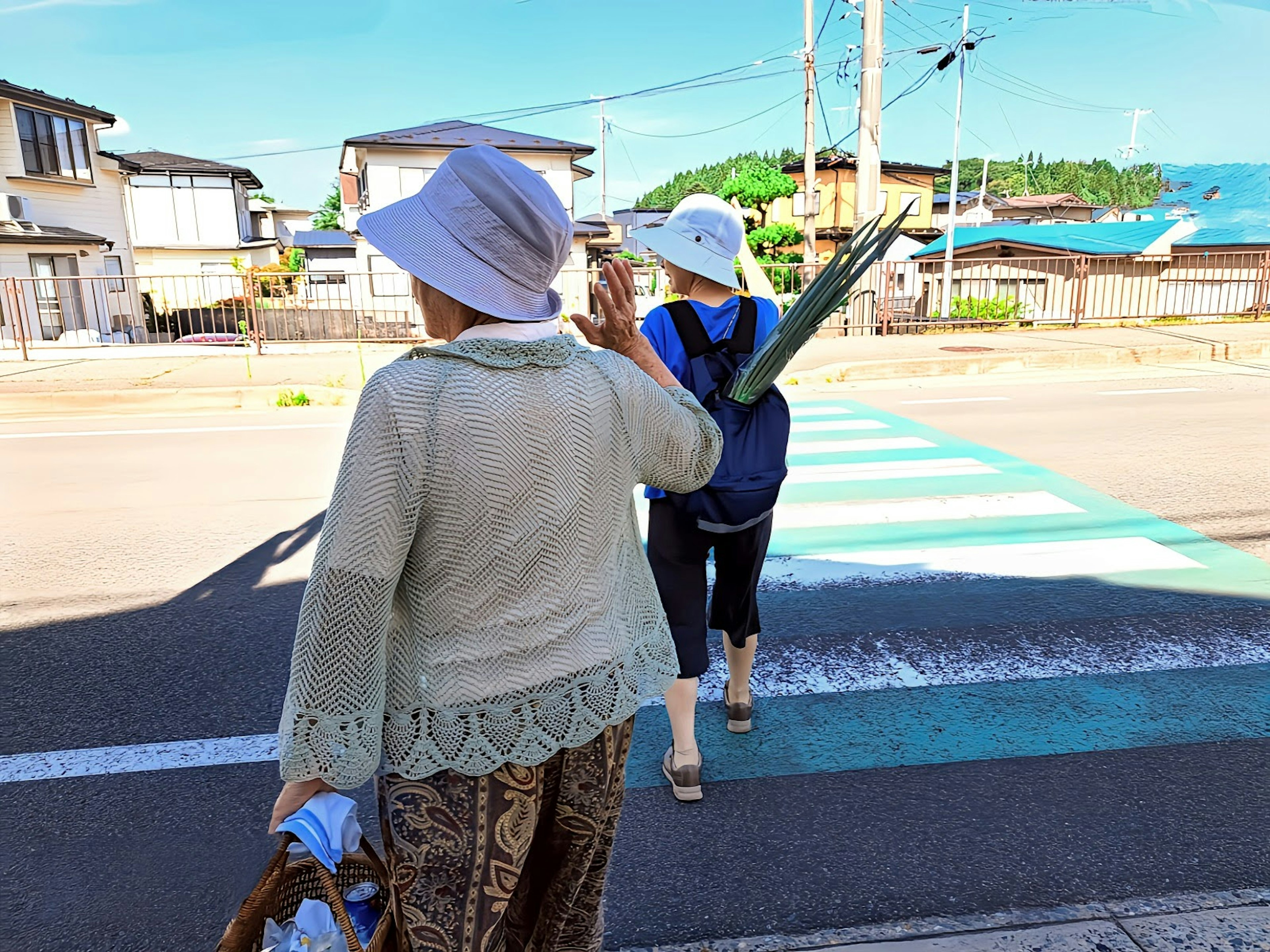 二人の女性が横断歩道を渡る風景 村の風景と青い空