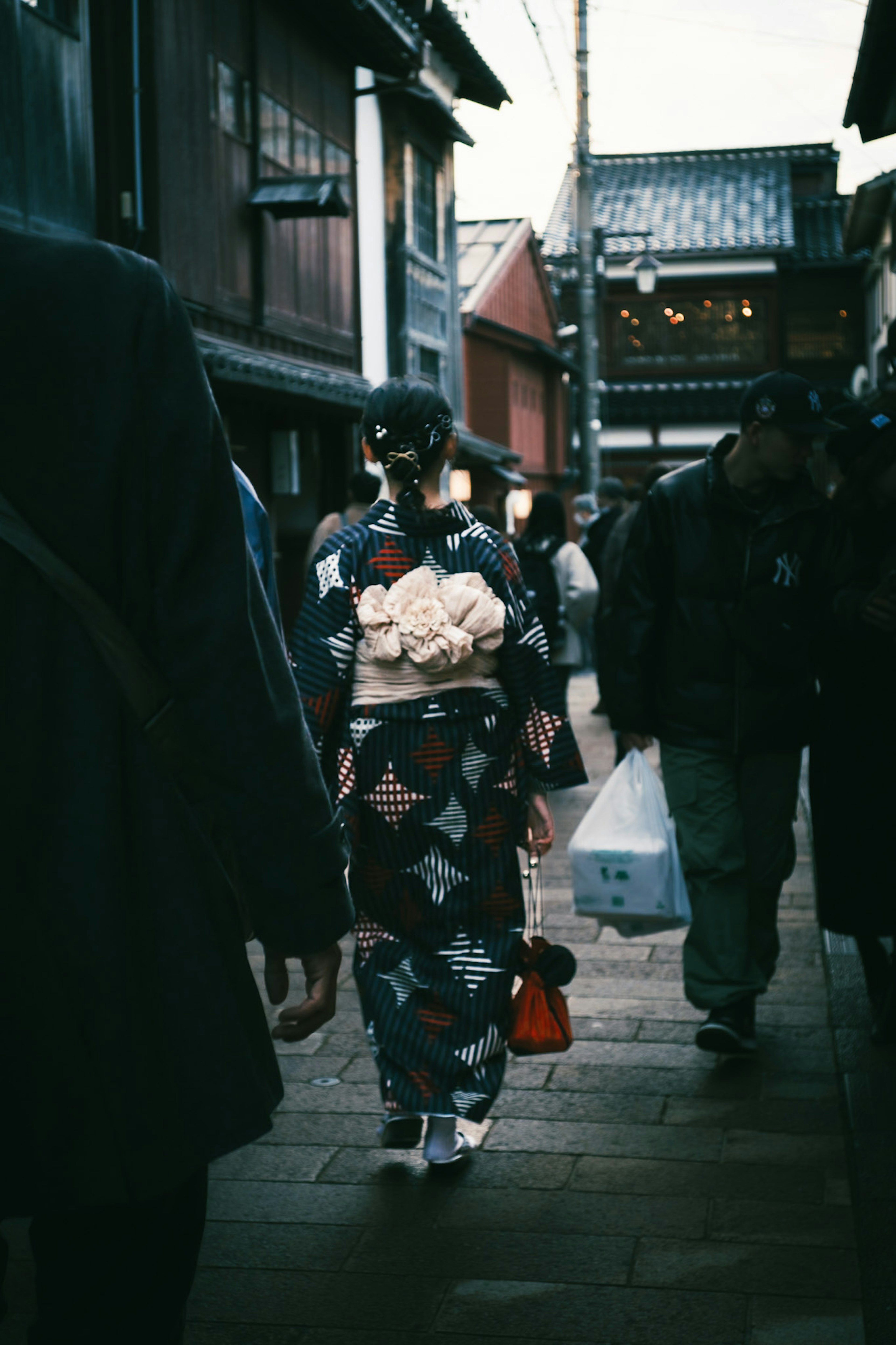 Seorang wanita berpakaian kimono berjalan di jalan tradisional