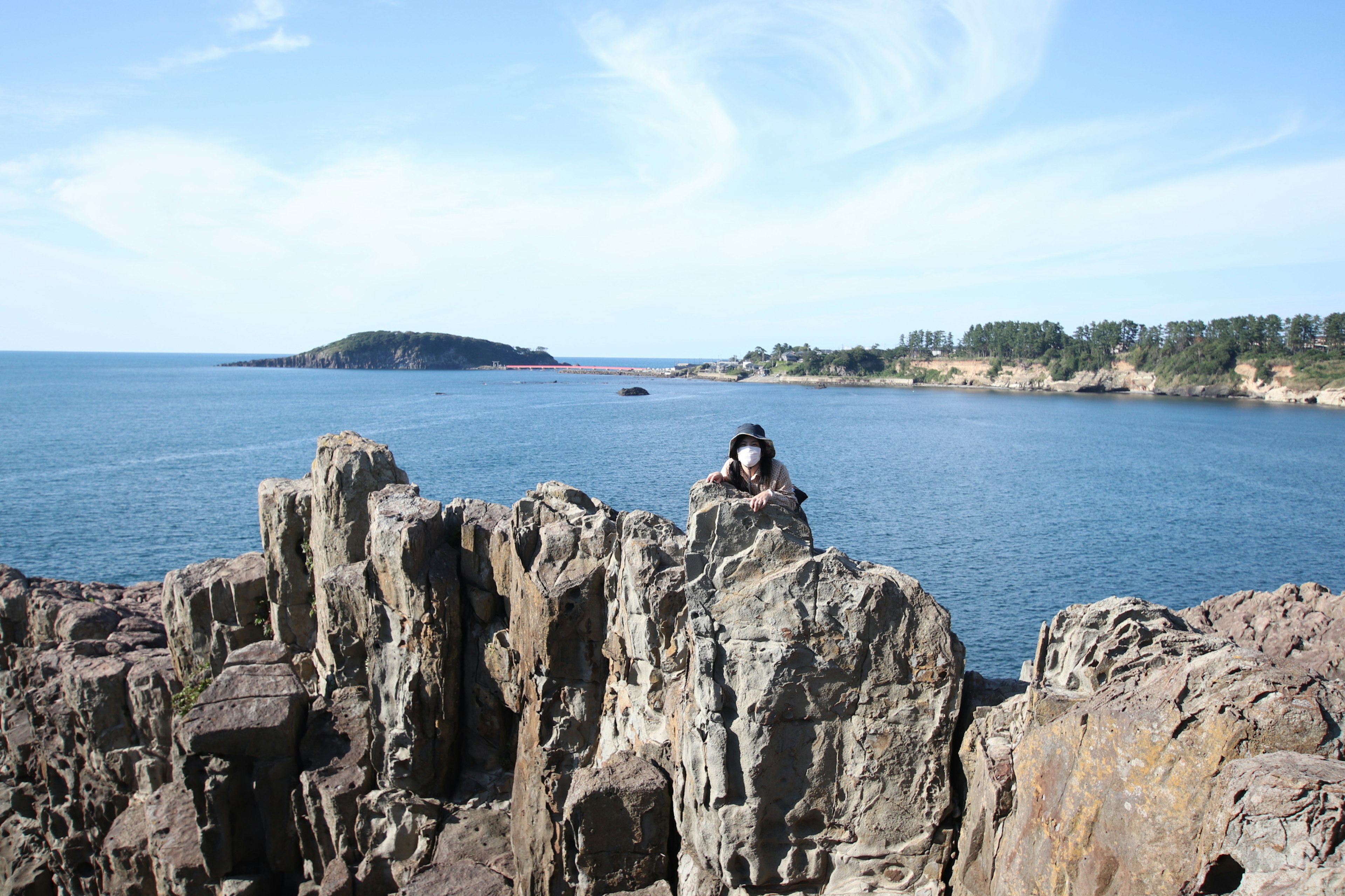 Persona de pie sobre rocas con fondo de mar azul