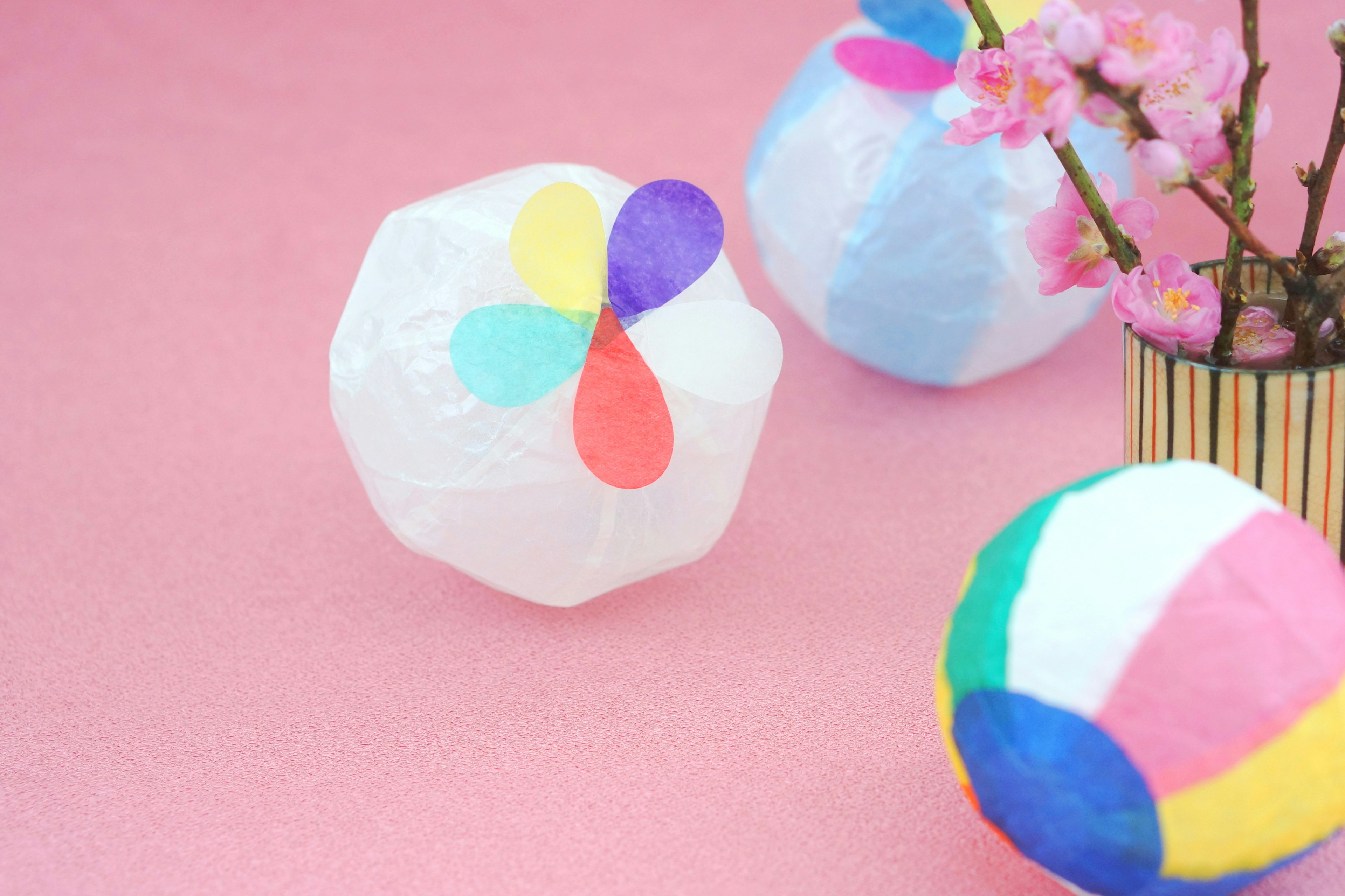 Bolas de papel coloridas y flores de cerezo en una mesa