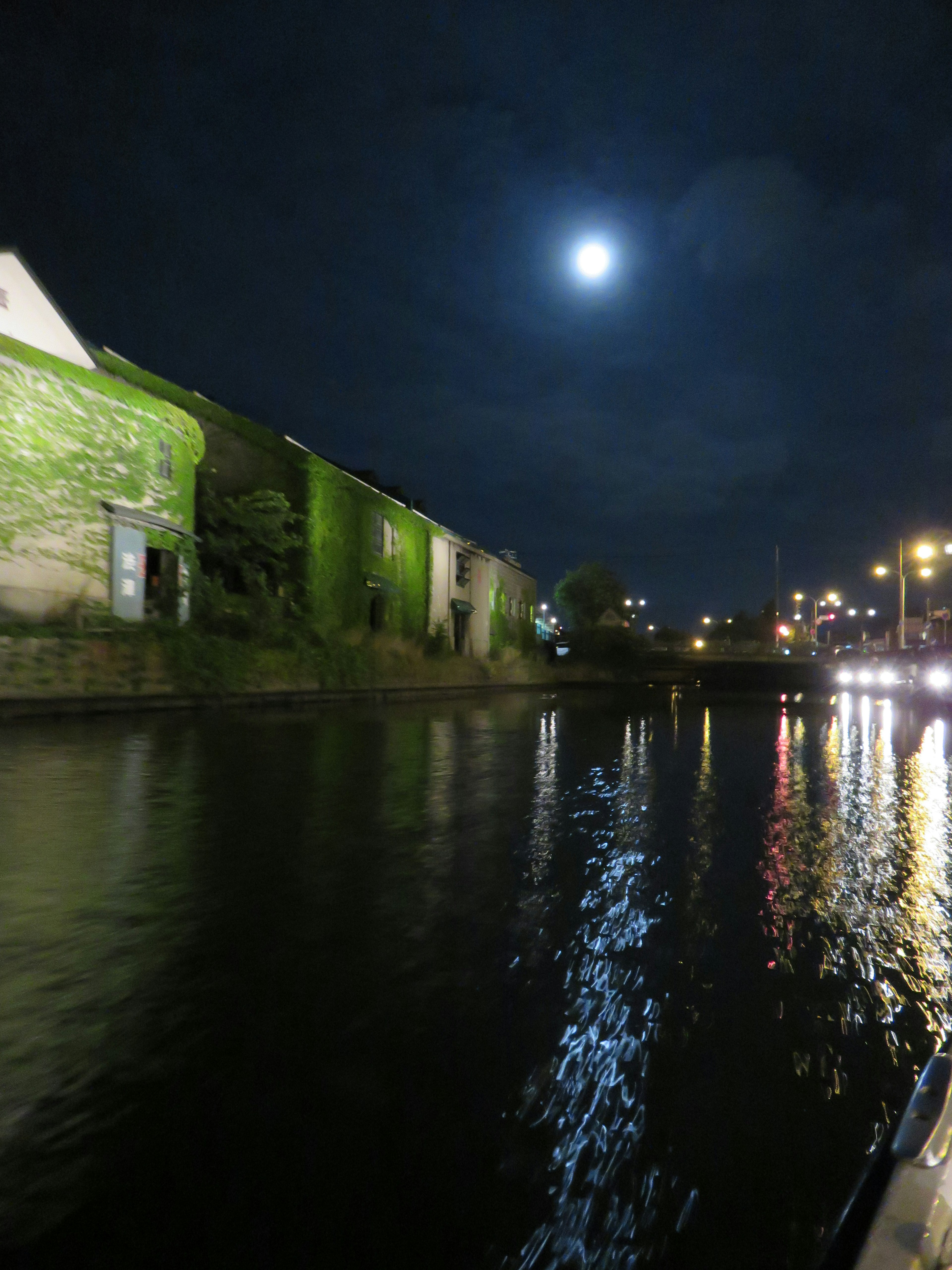 Vista nocturna de un canal iluminado por la luna reflejada en el agua