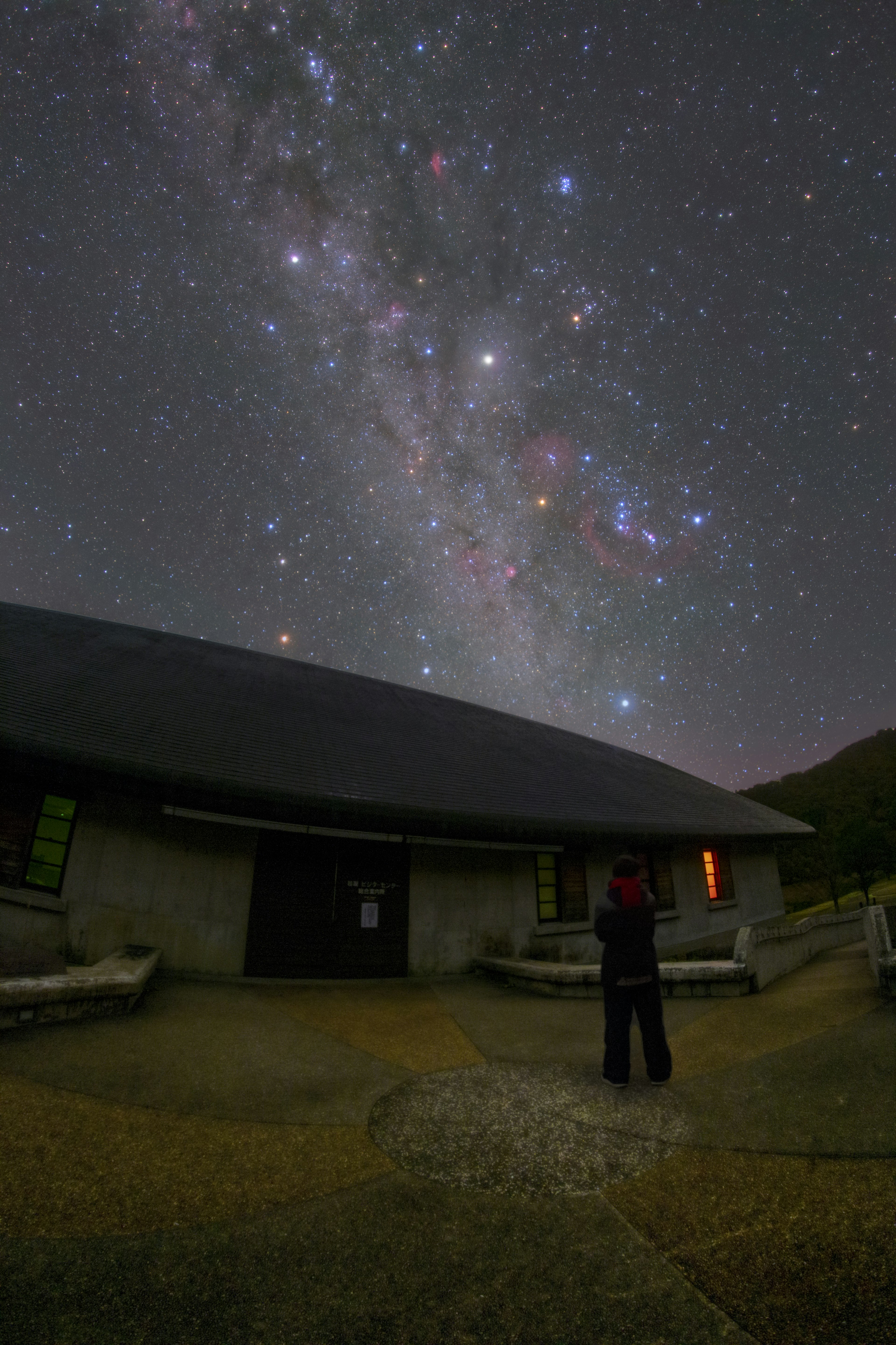 星空の下で建物を見上げる人物 美しい天の川が広がる夜空