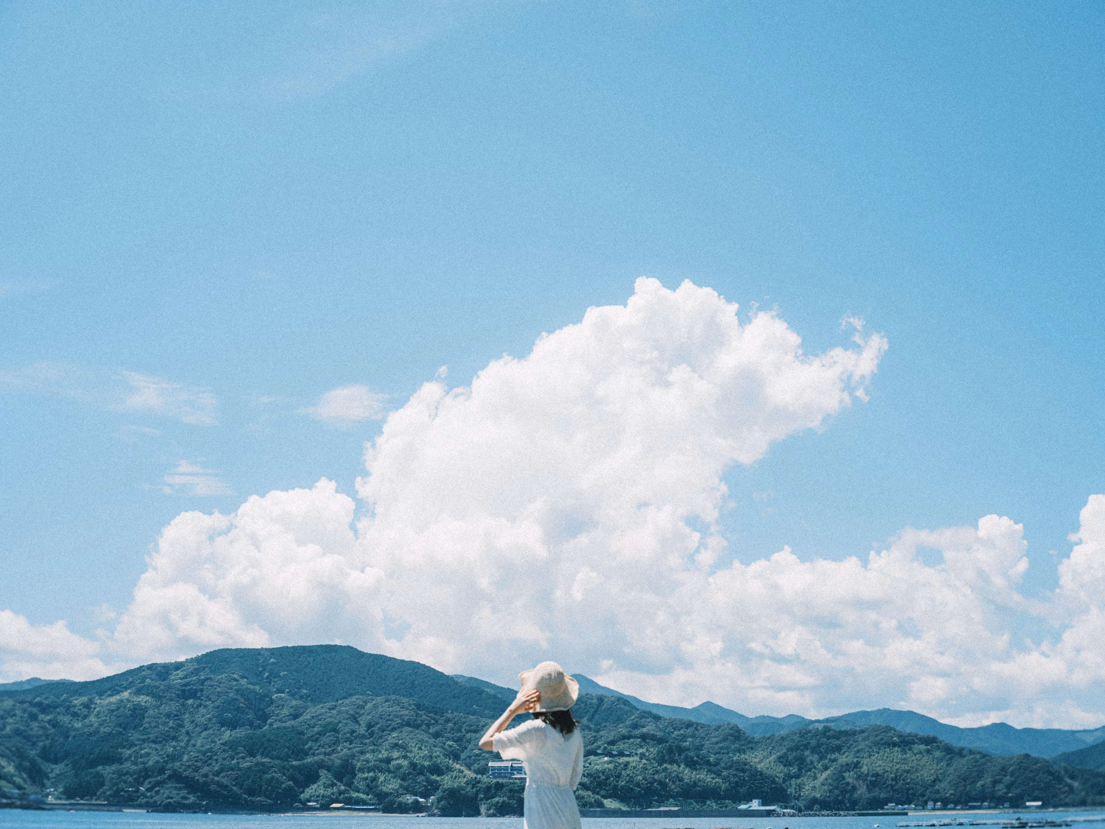 女性在藍天和雲朵下站在山前