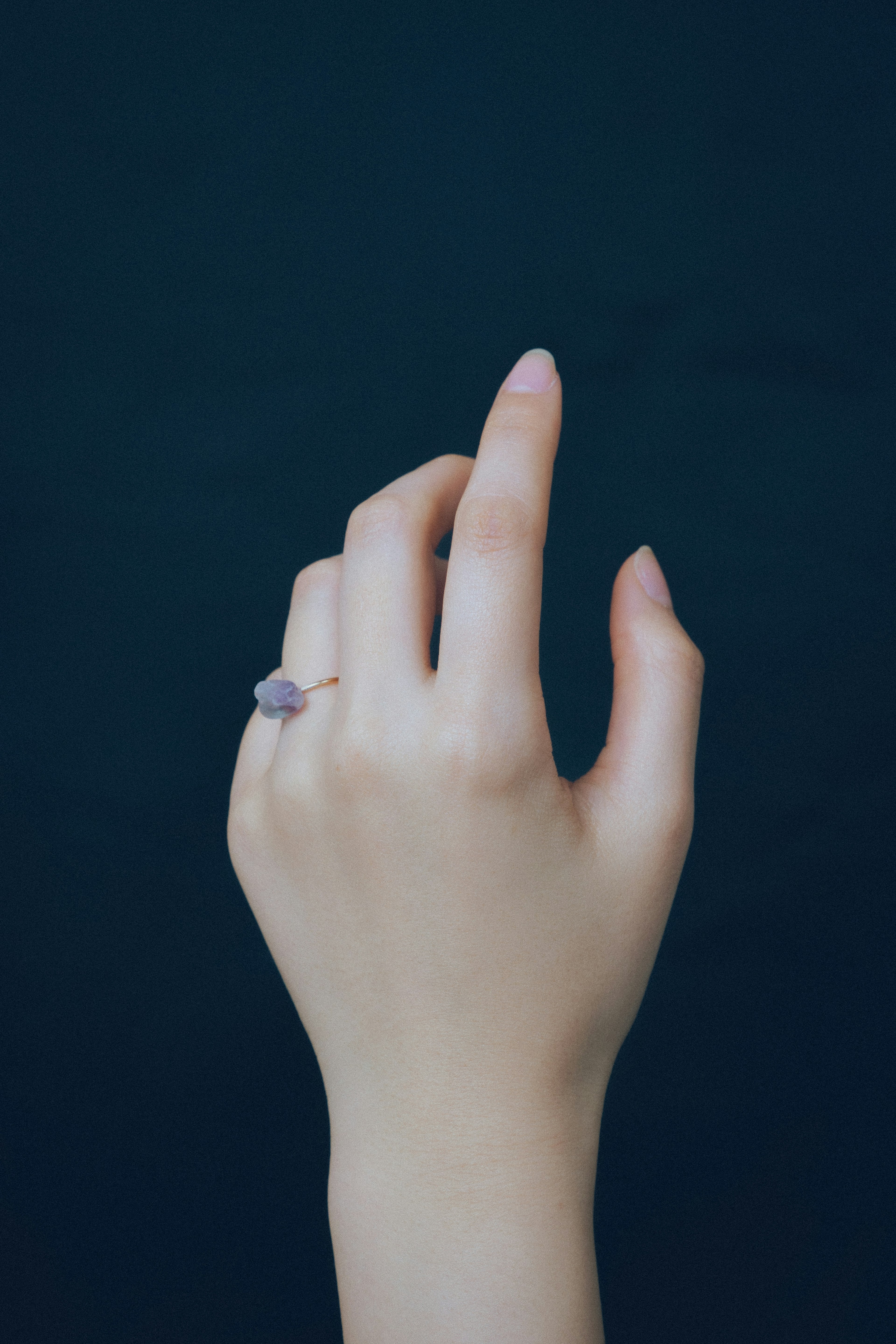 Hand with a ring displayed against a blue background