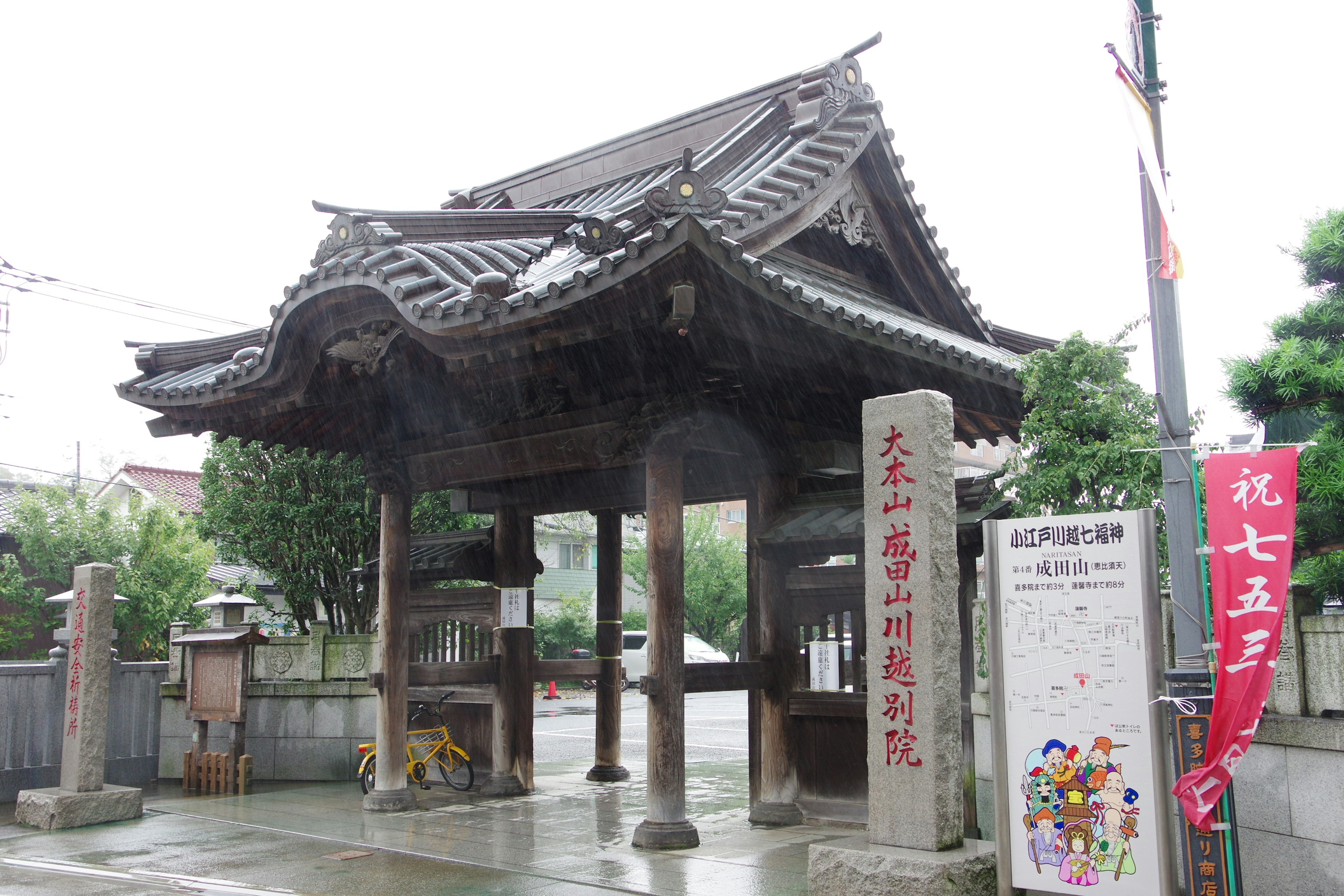 傳統日本門，瓦屋頂和木柱，周圍是雨中的綠色植物