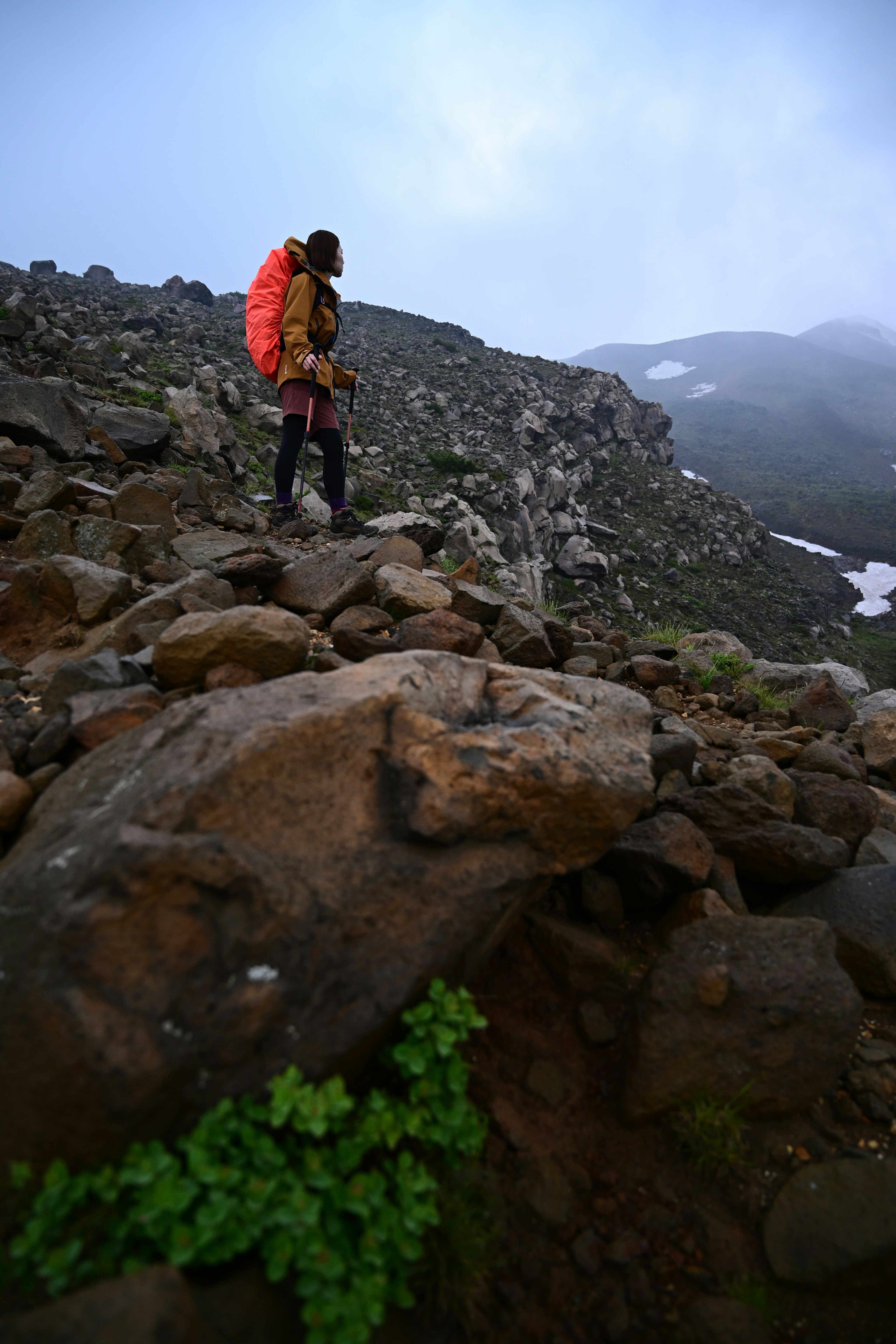 Hiker navigating rocky terrain with foggy mountain backdrop