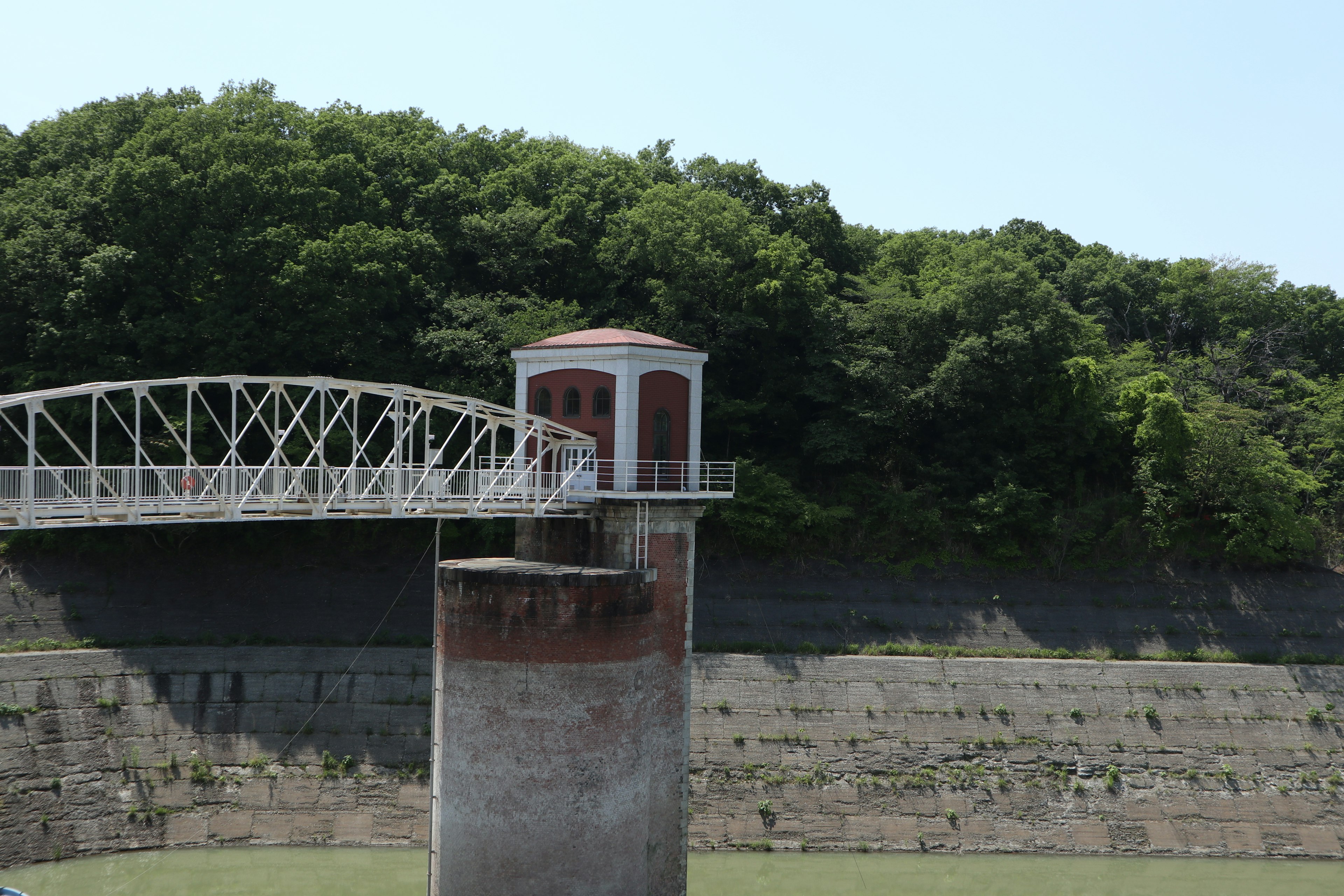 緑豊かな背景の水門とその上の歩道