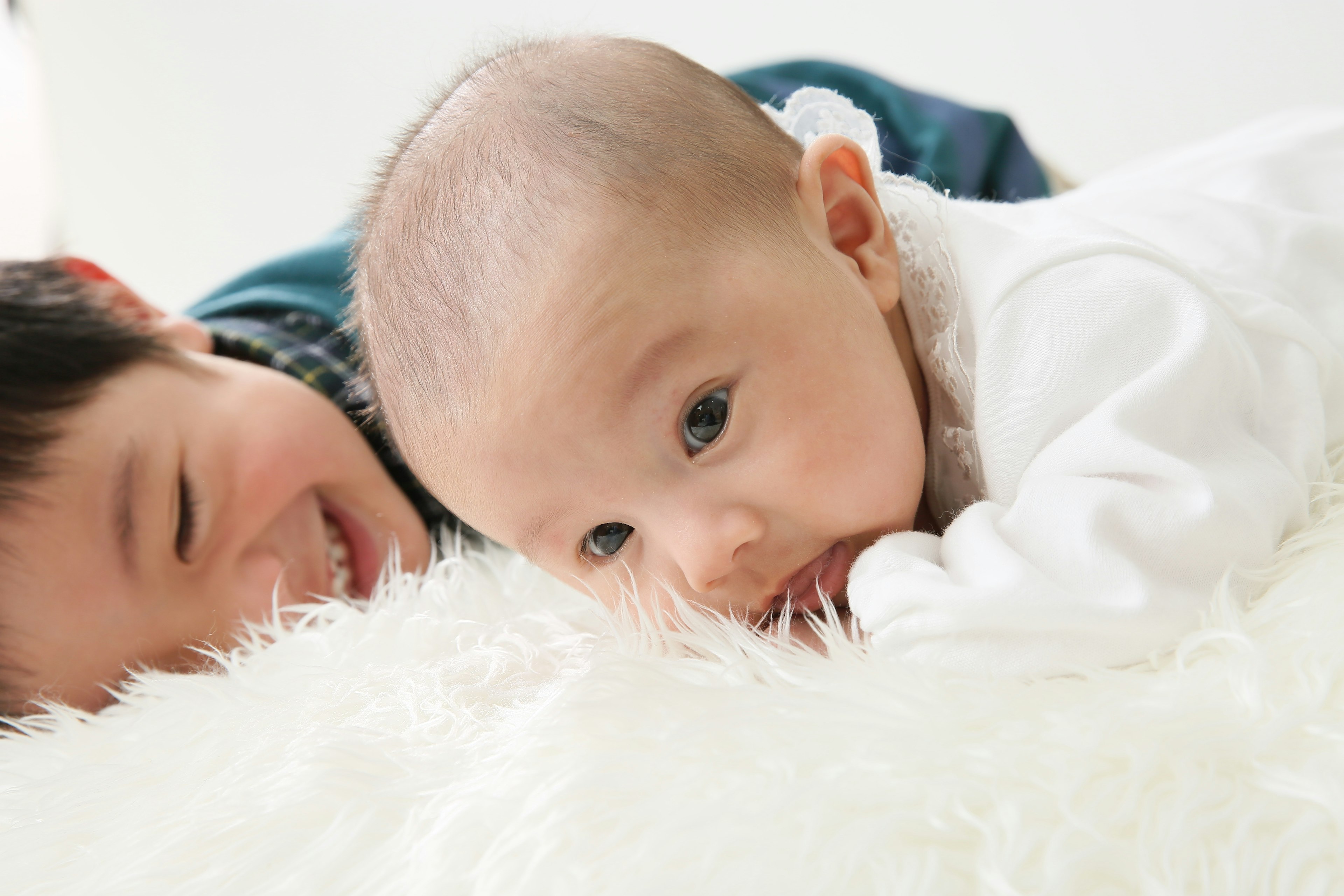 A baby and a child playing on a fluffy blanket