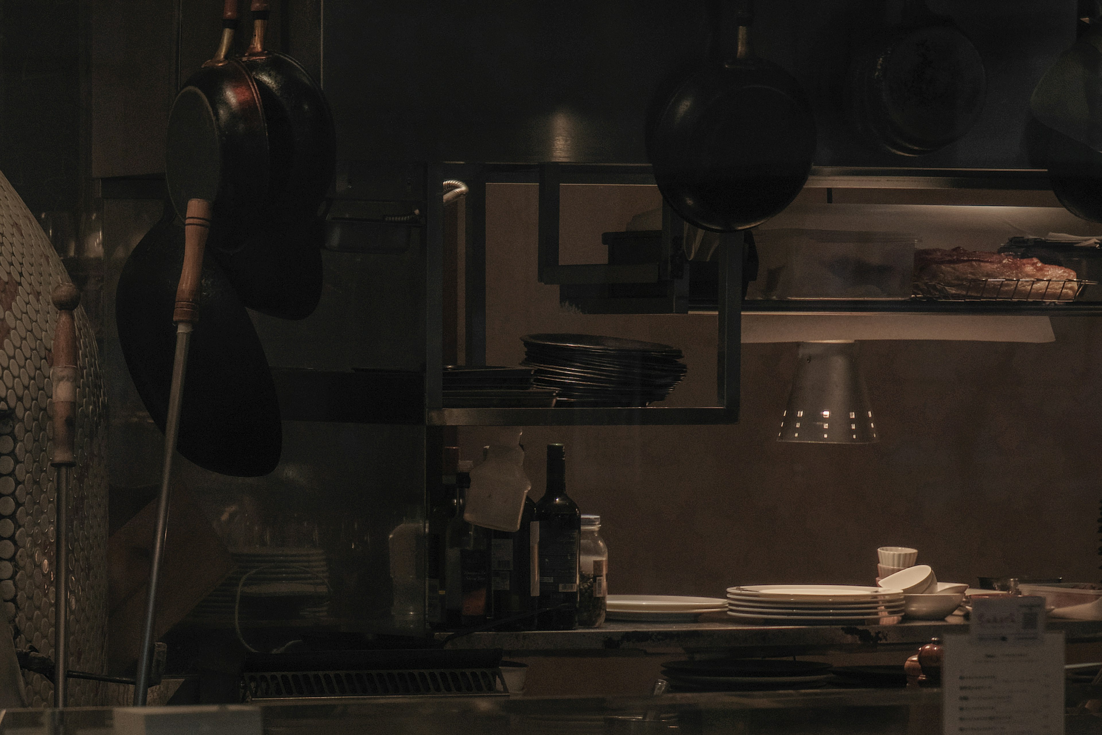 Dimly lit kitchen interior featuring pots and plates