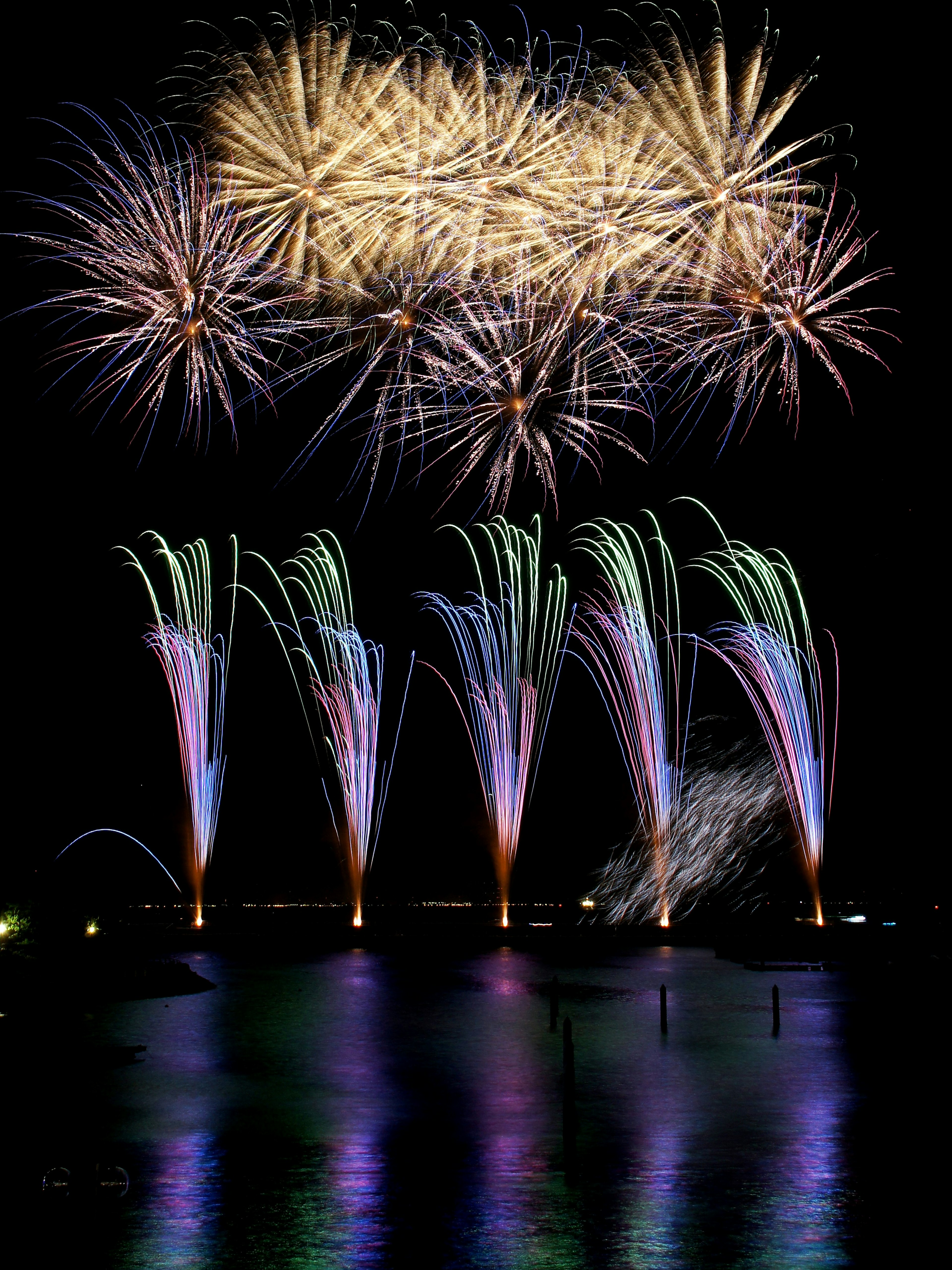 Spettacolo di fuochi d'artificio colorati sopra l'acqua con fontane vivaci