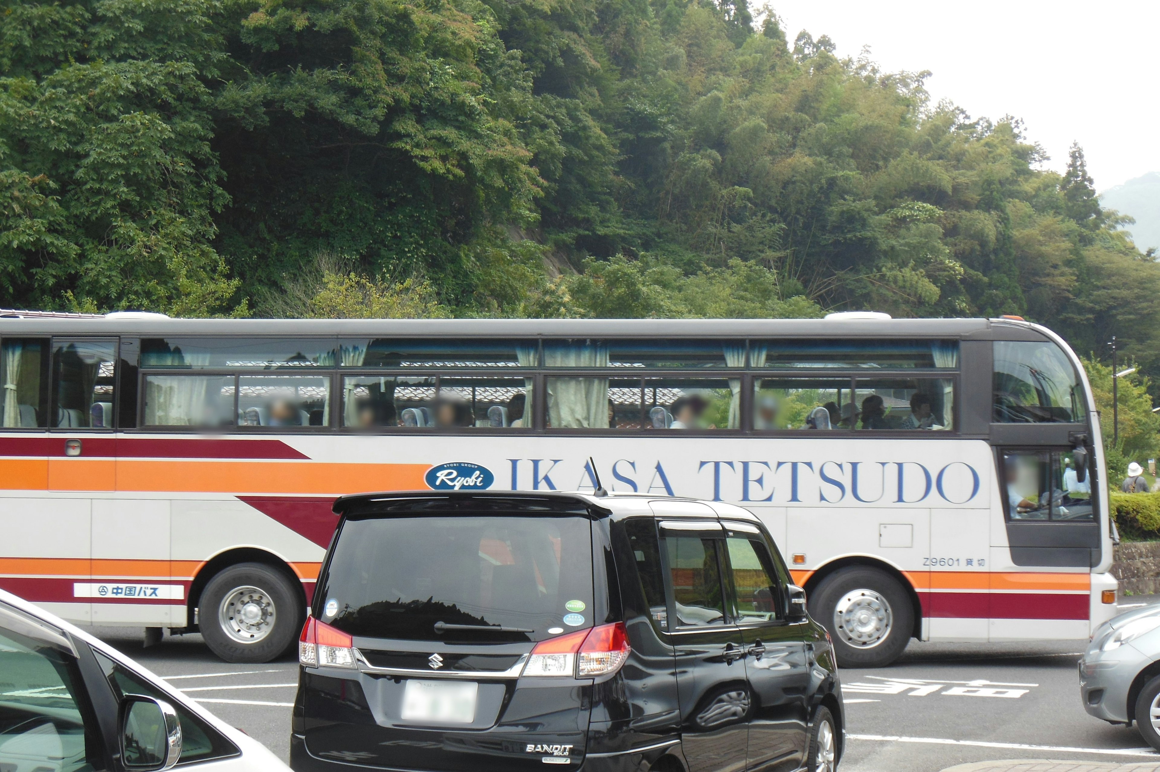 Sebuah bus dan mobil hitam di tempat parkir