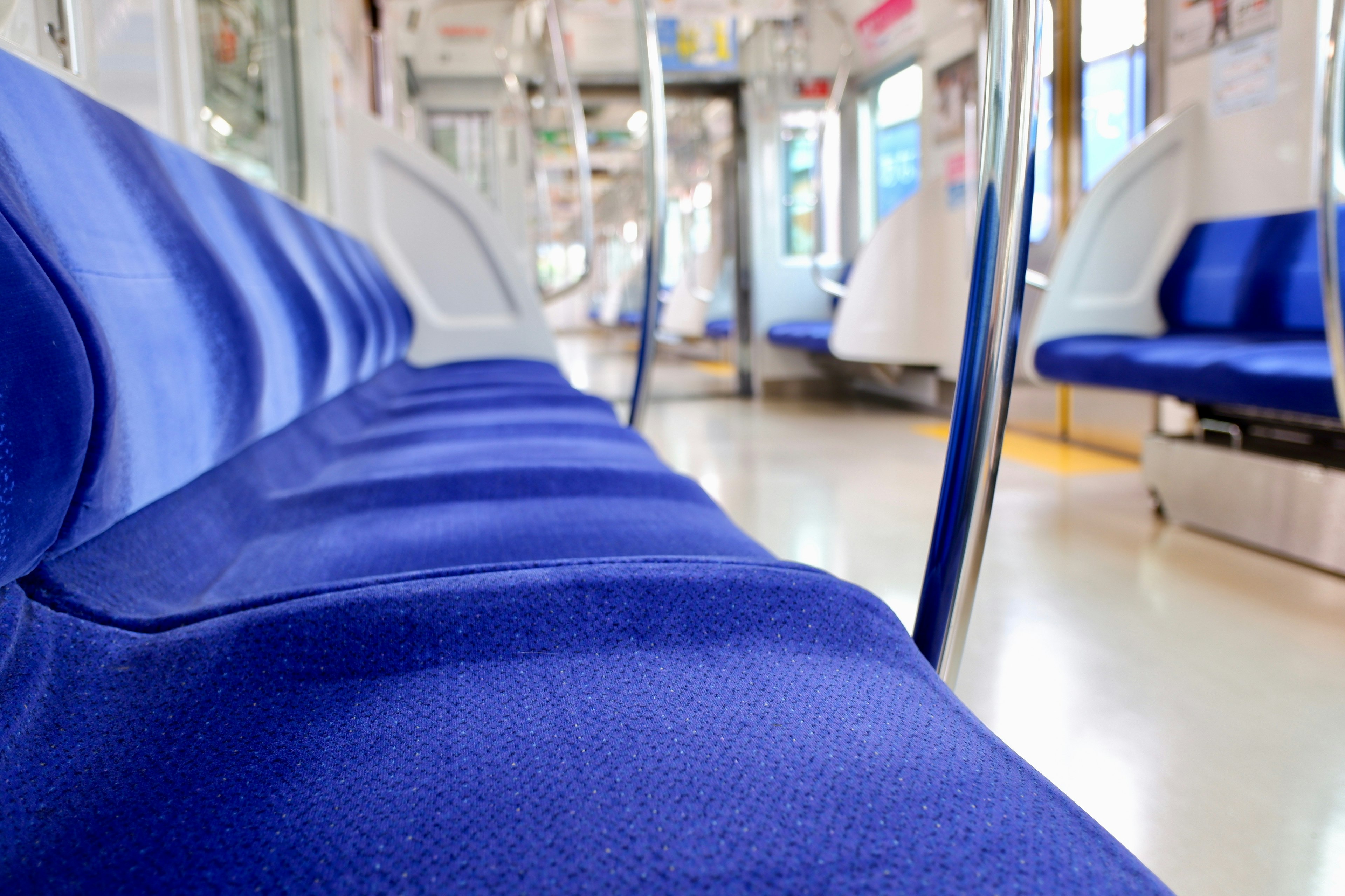 青いシートが並ぶ空の電車の車両の内部