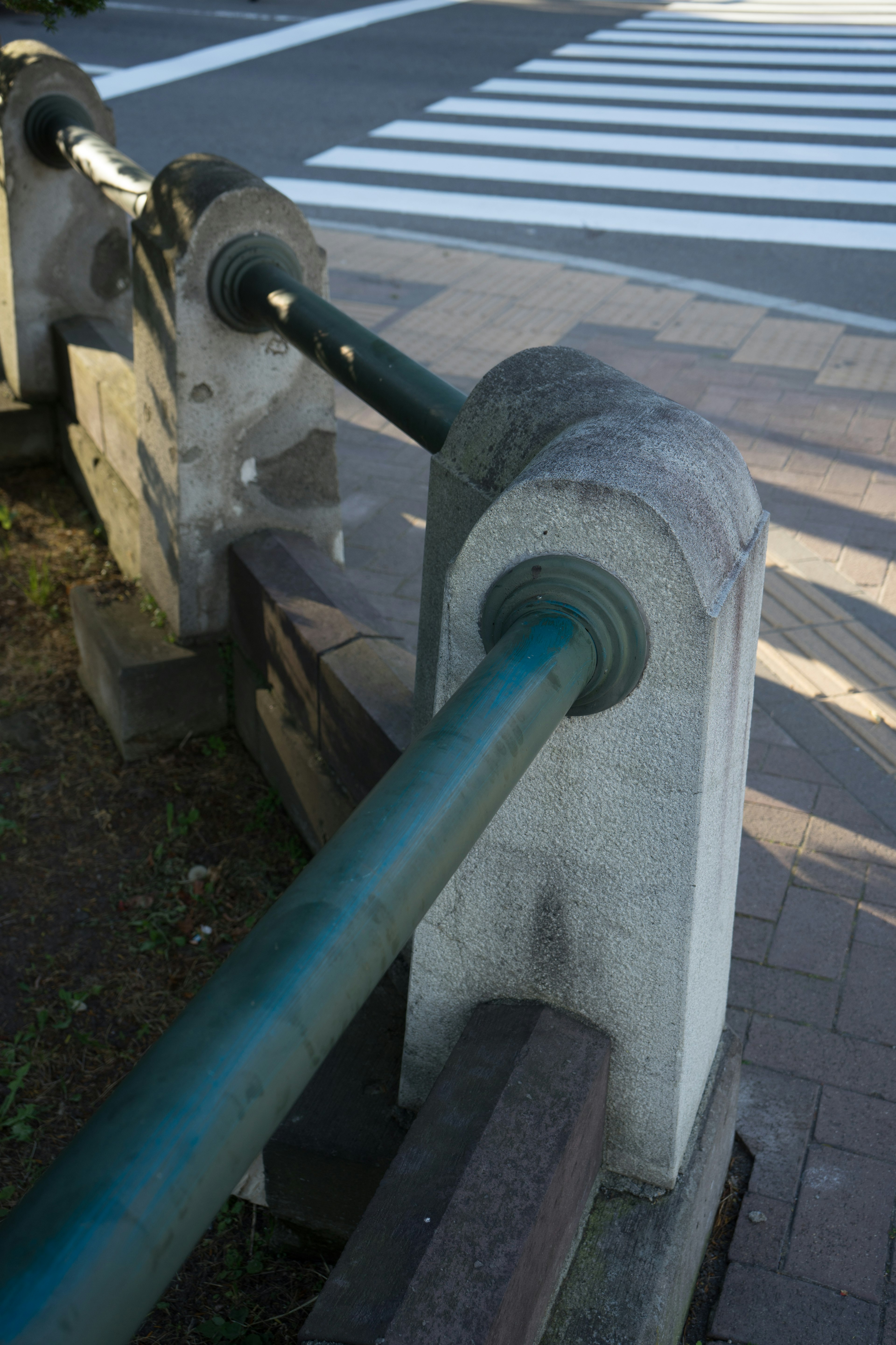 青い手すりと石の柱がある歩道の一部