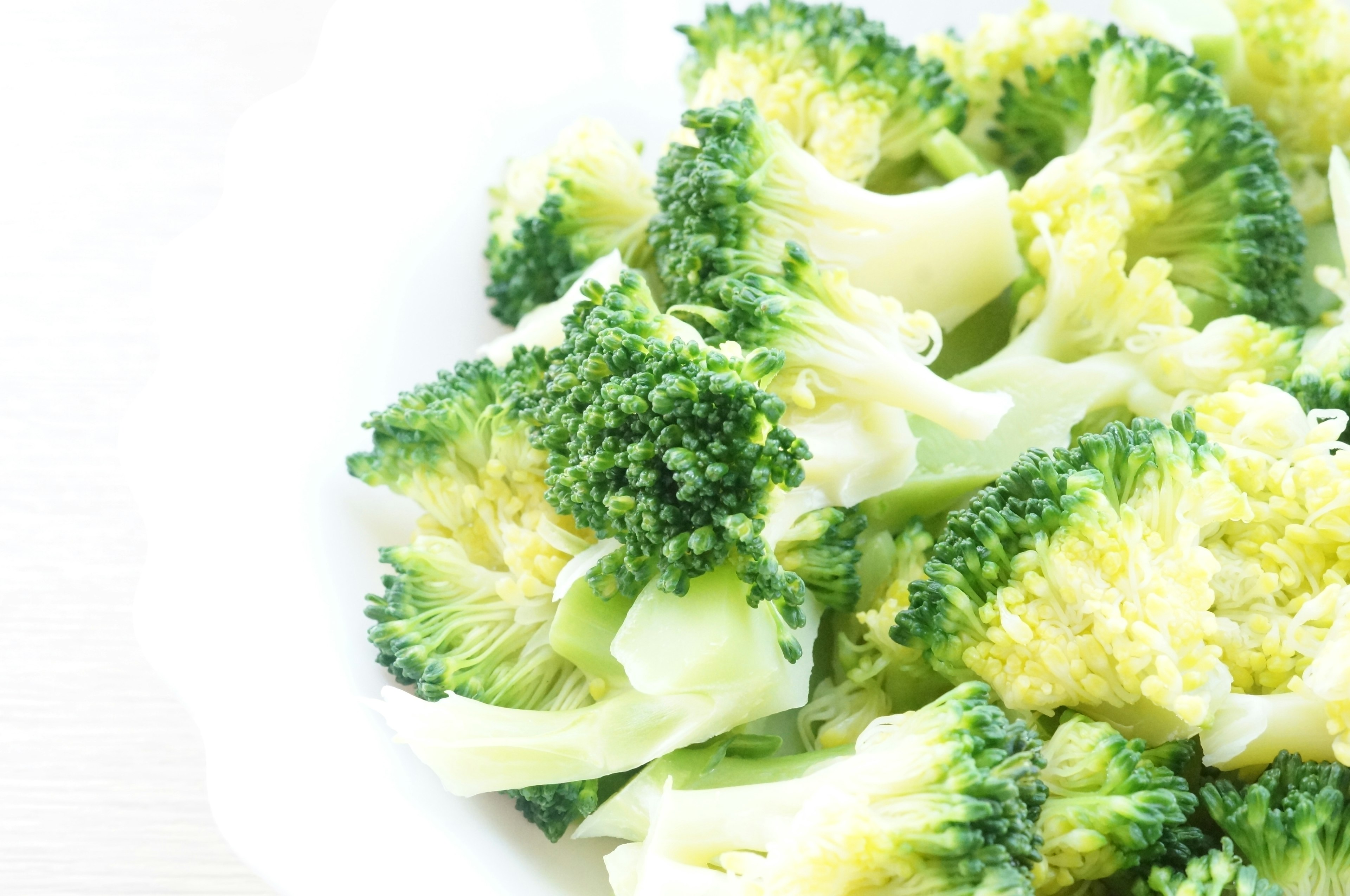 Freshly cut broccoli florets on a white plate