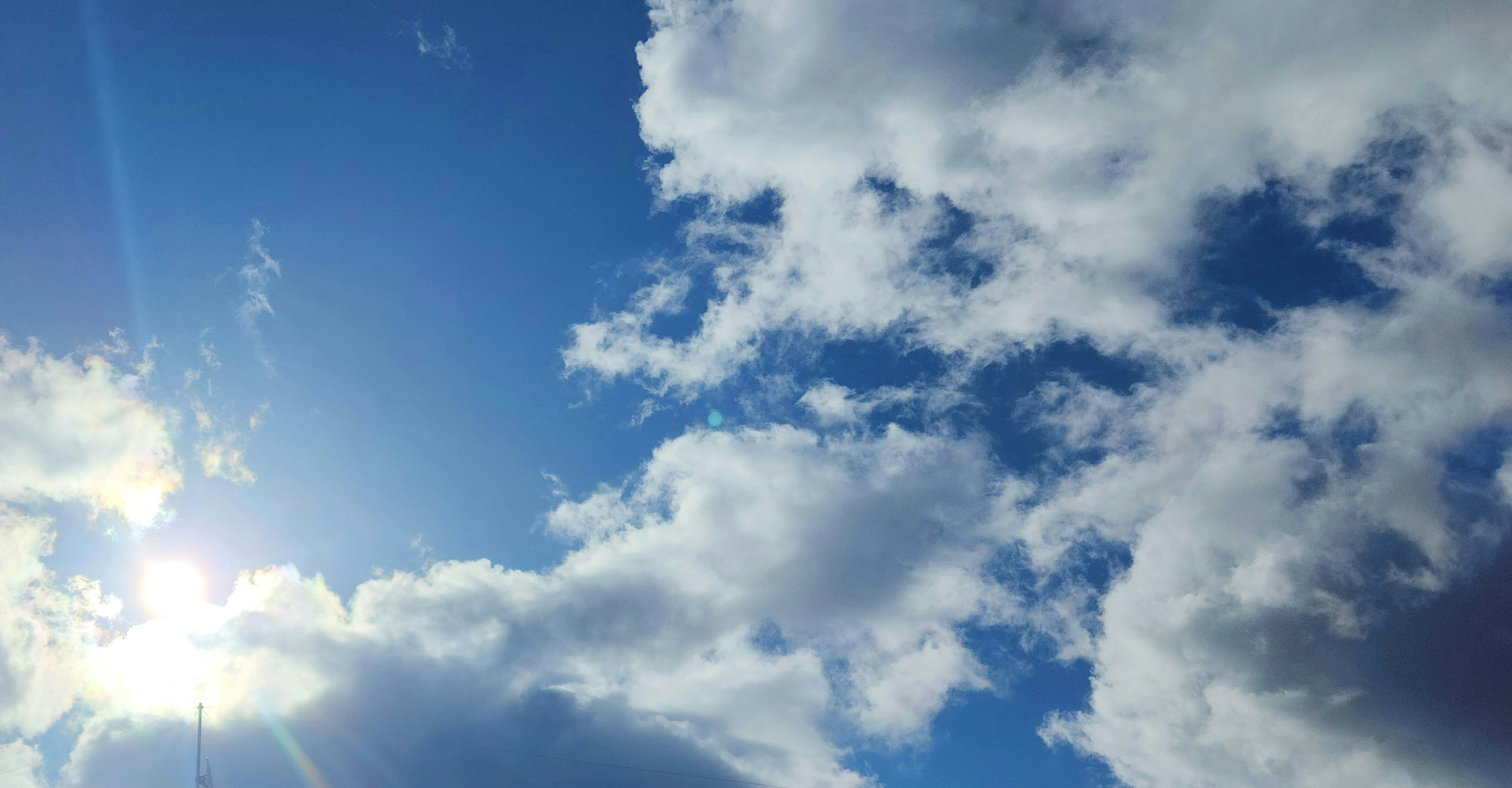 White clouds in a blue sky with sunlight shining