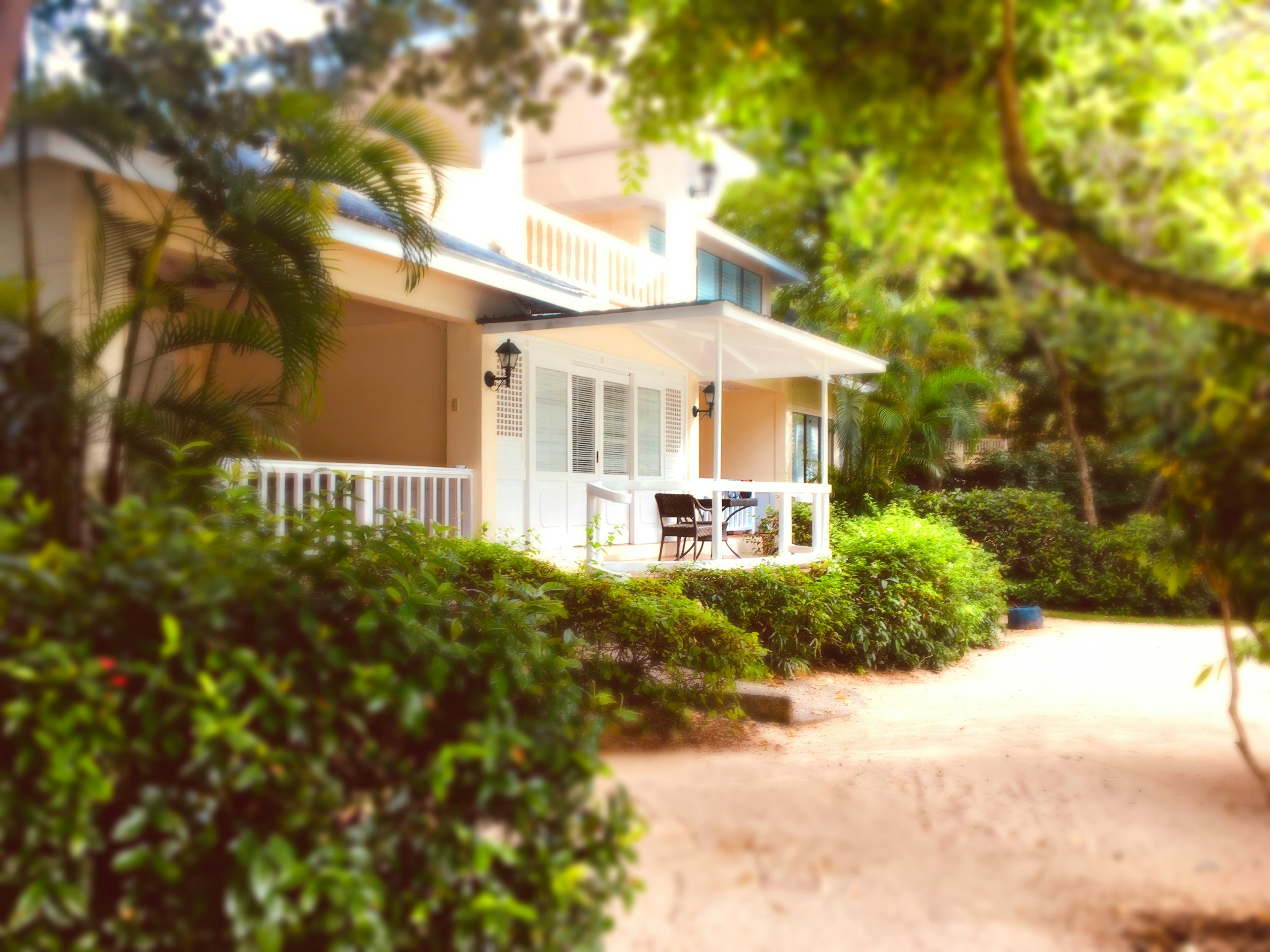 Maison avec un balcon blanc entourée de verdure luxuriante