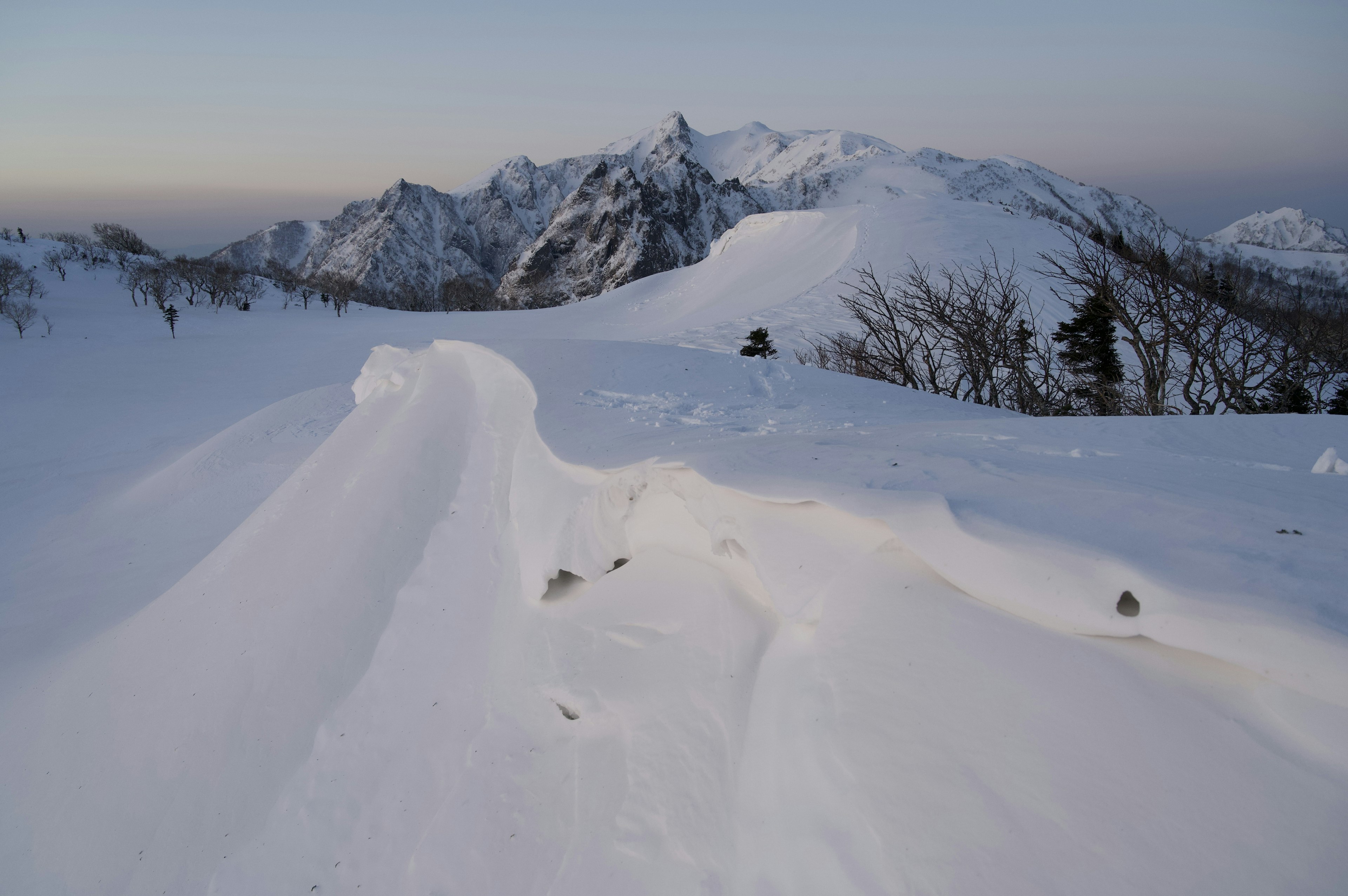 Paisaje montañoso cubierto de nieve con superficie de nieve ondulante