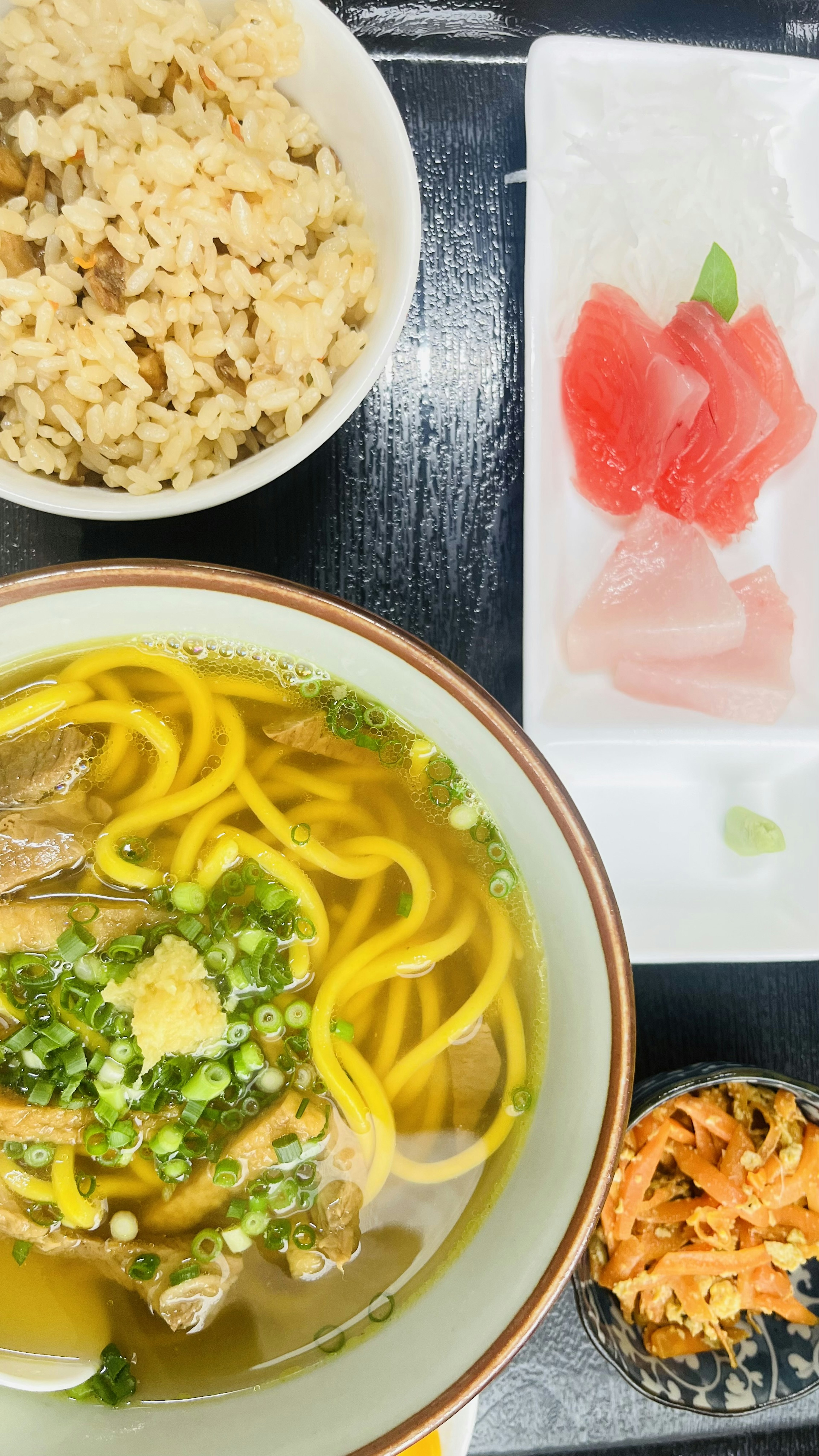 ラーメン、白ご飯、刺身、野菜サラダの皿が並んだ食事