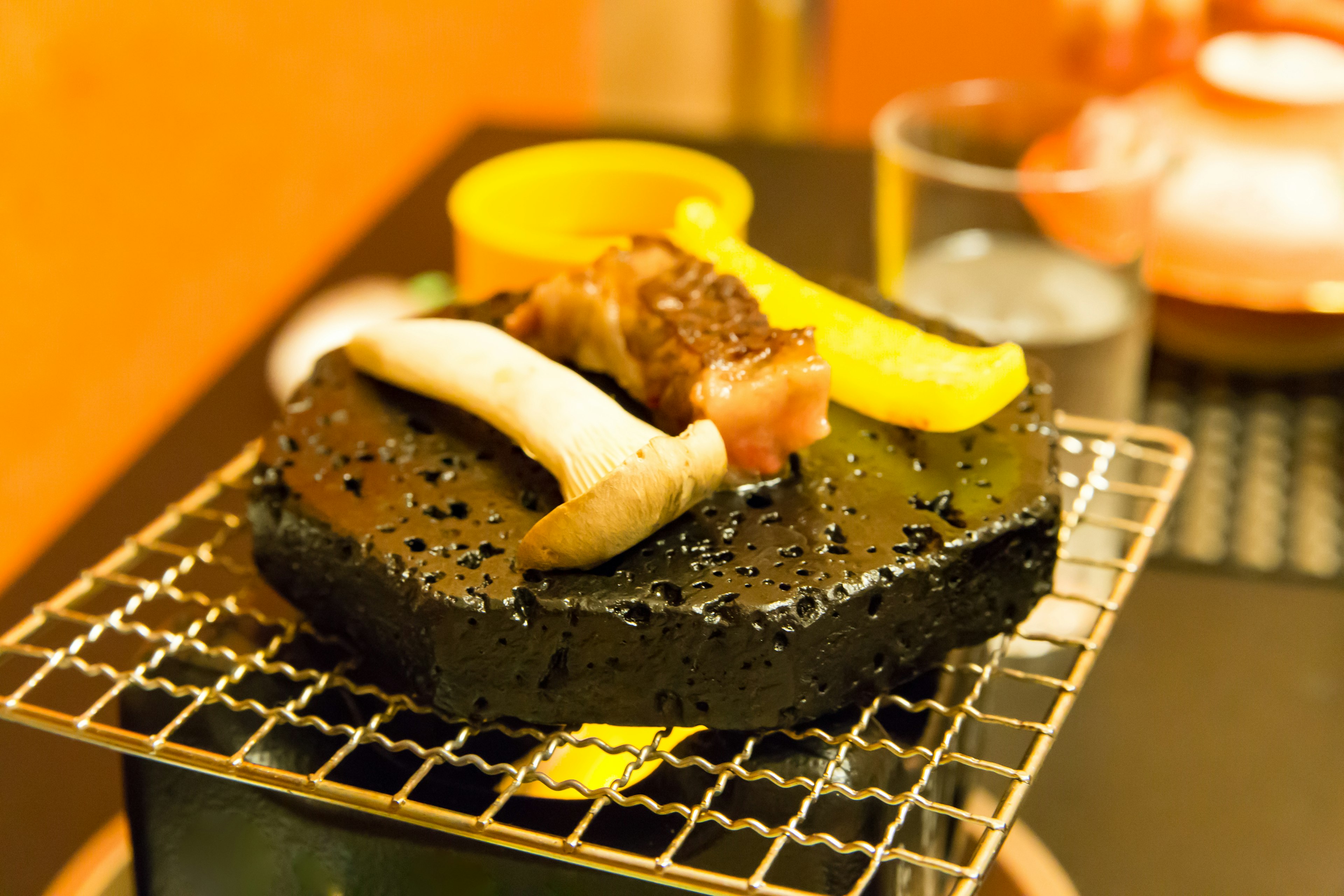 黒い石の上に焼かれた肉と野菜の料理