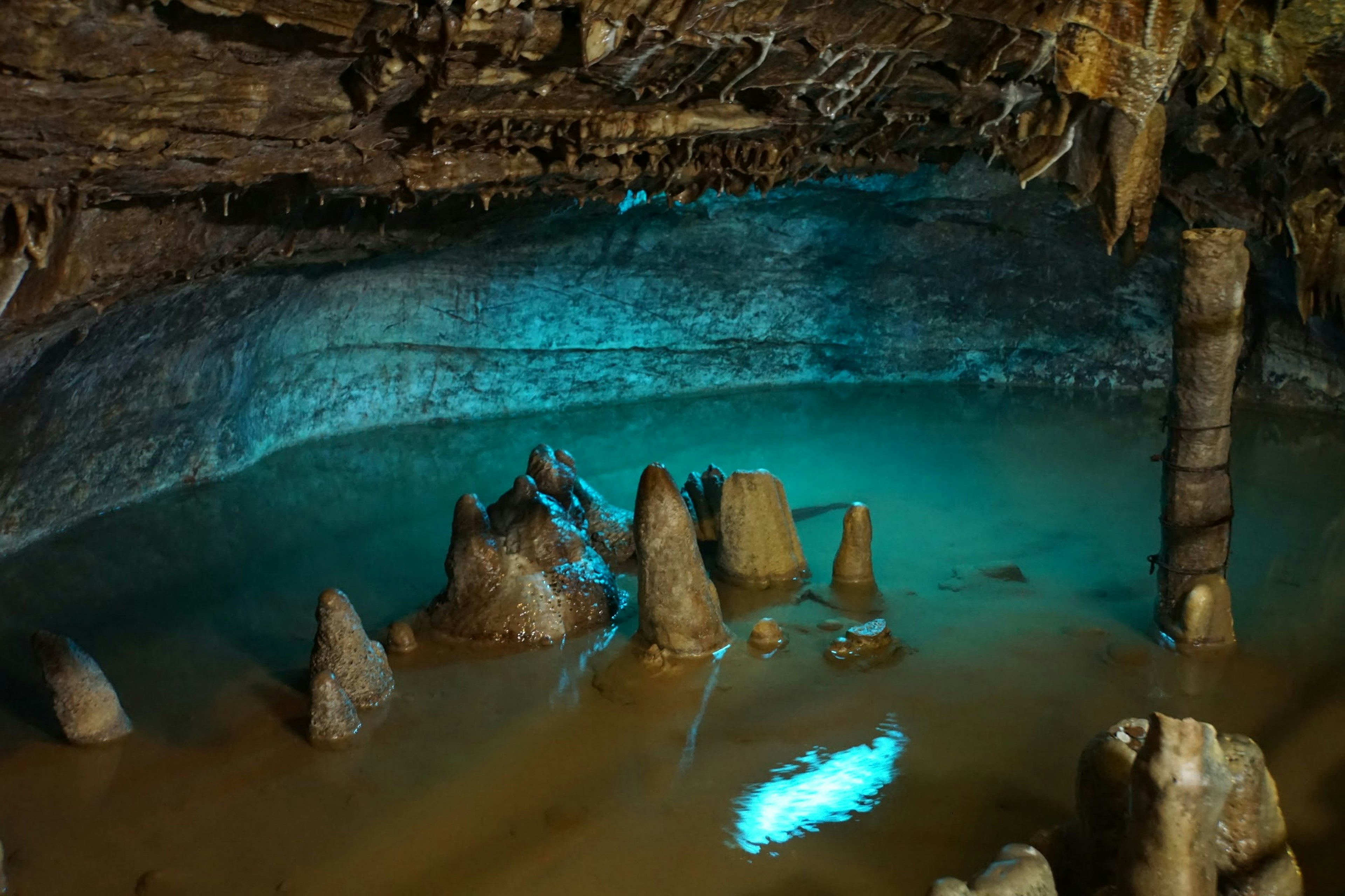 Área de agua subterránea iluminada por luz azul y estalagmitas