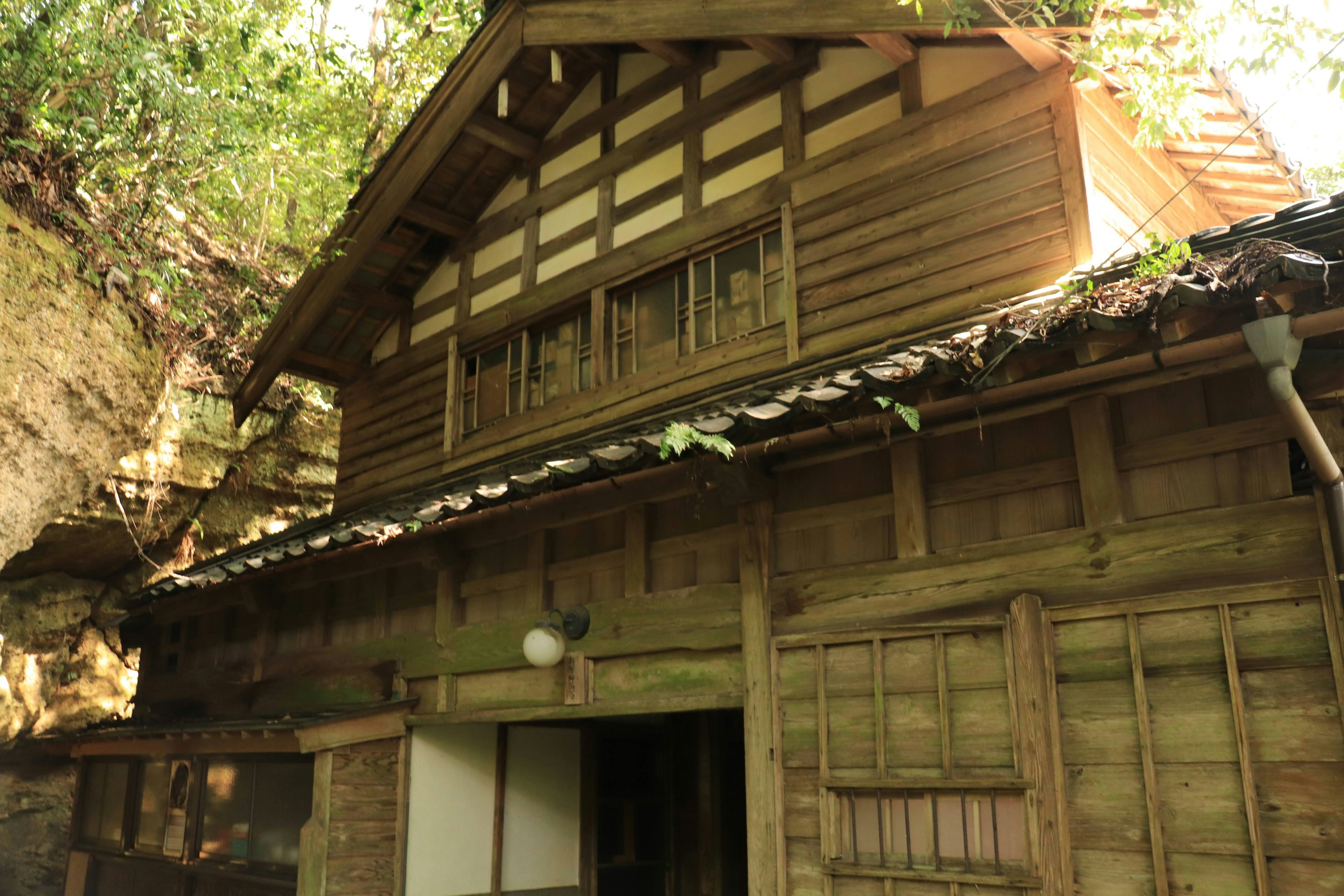 Eksterior rumah kayu Jepang tradisional dikelilingi oleh vegetasi