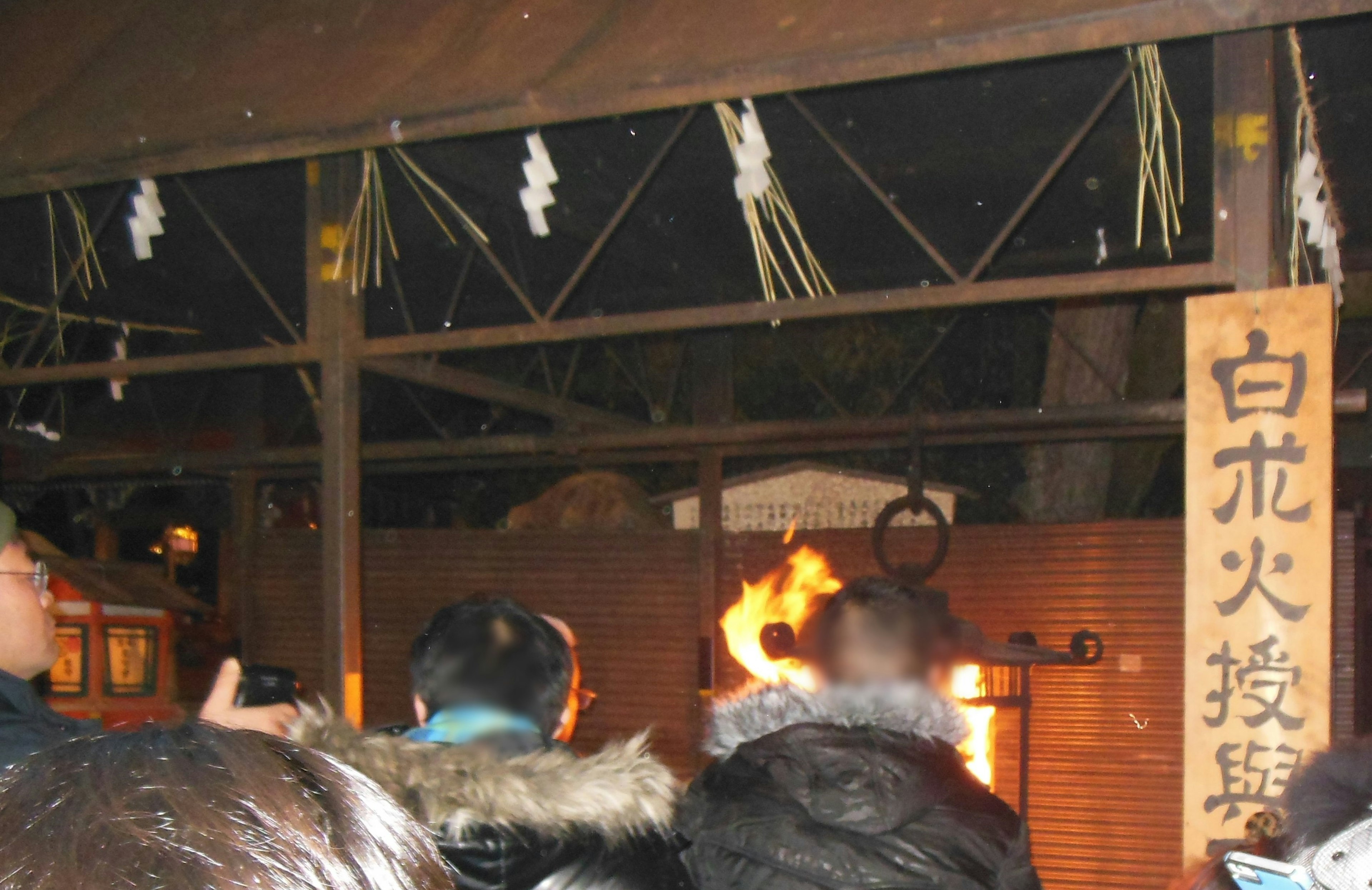 Scene of a shrine ritual with flames and spectators from behind