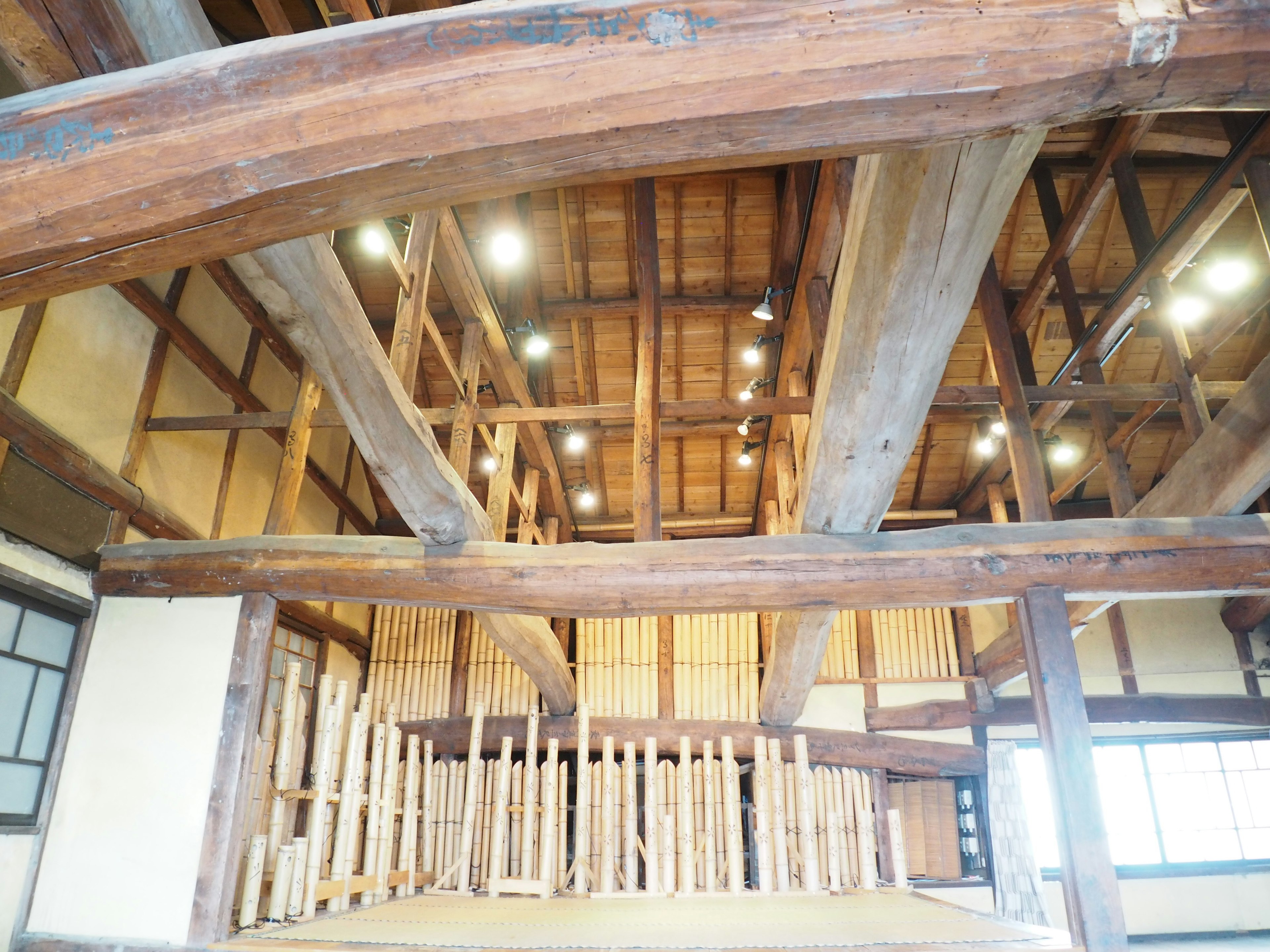 Struktur interior rumah tradisional Jepang dengan balok kayu dan langit-langit yang diterangi cahaya alami