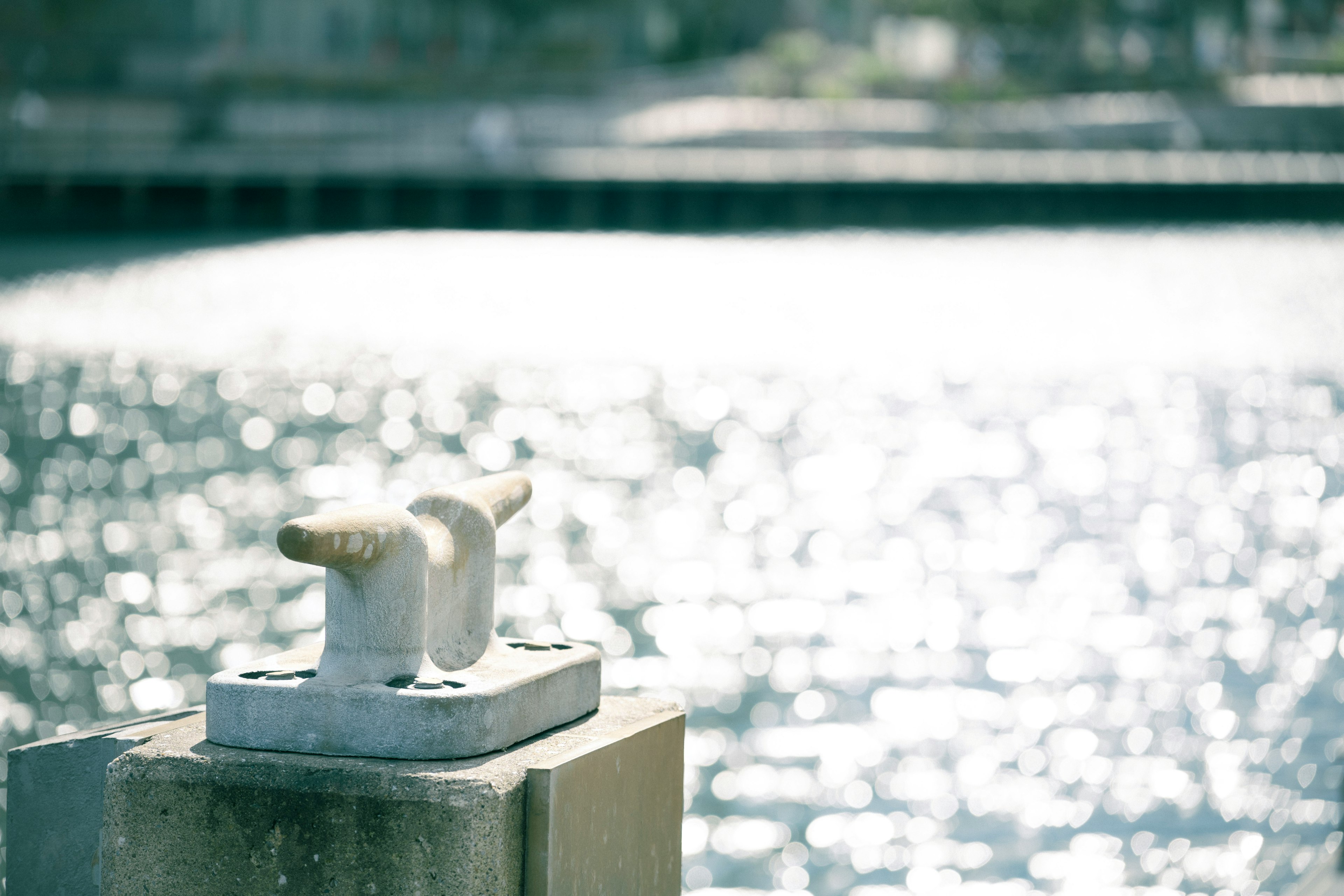 Close-up of a dock bollard with shimmering water surface