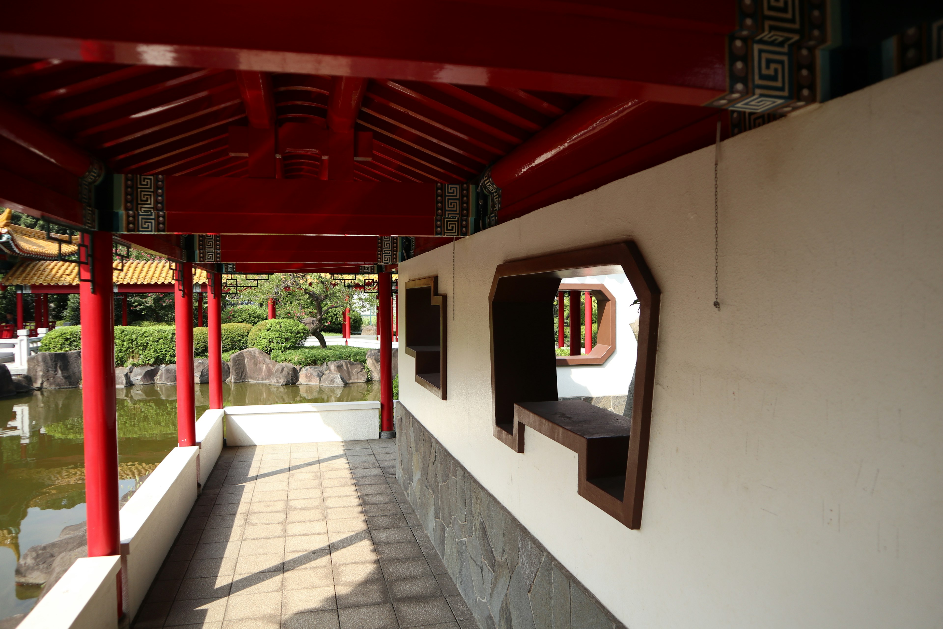 Chinese-style corridor with a red roof and white walls featuring square windows