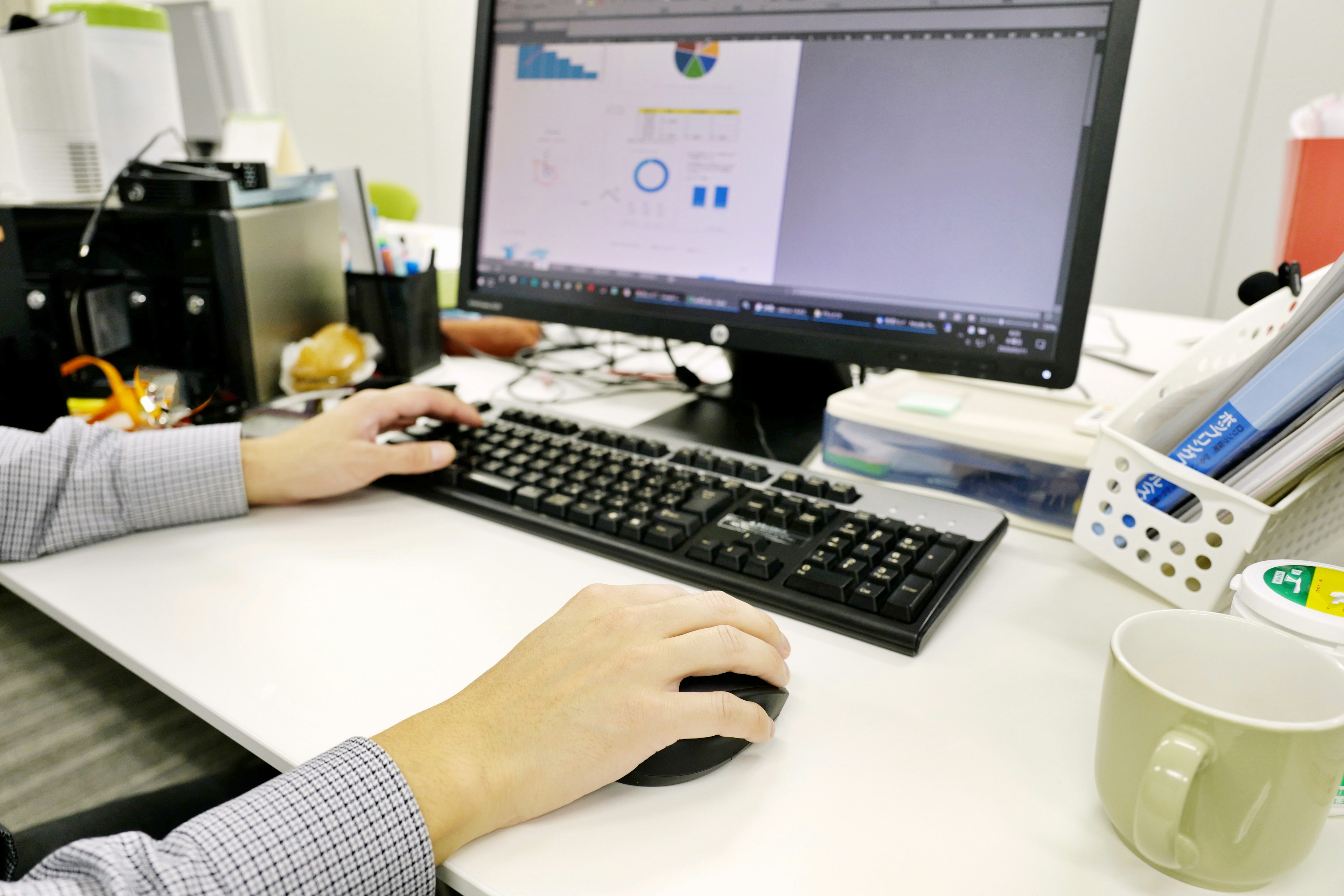 Hand using mouse on desk with computer screen displaying a chart