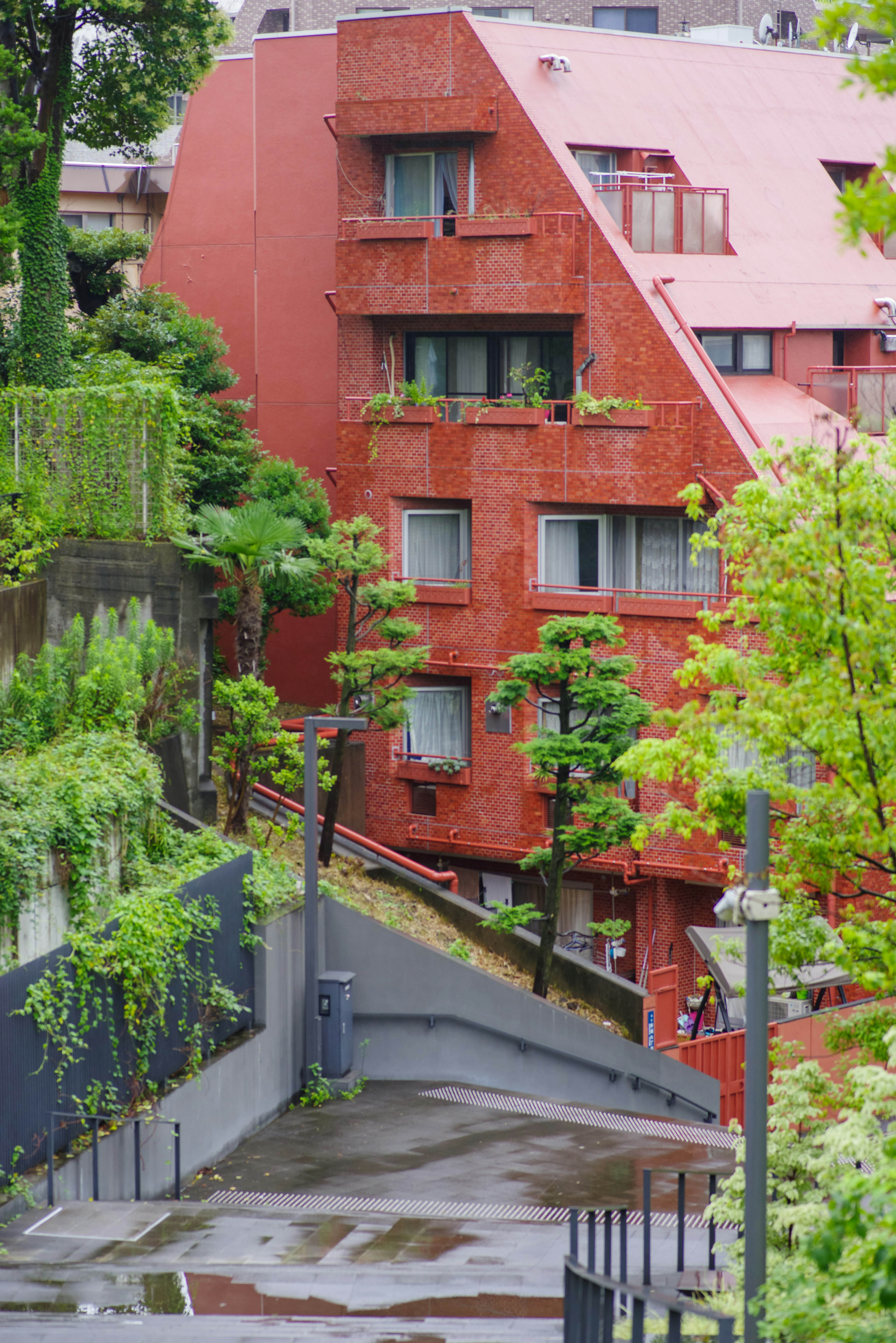 Bâtiment rouge angulaire avec des plantes vertes dans le paysage