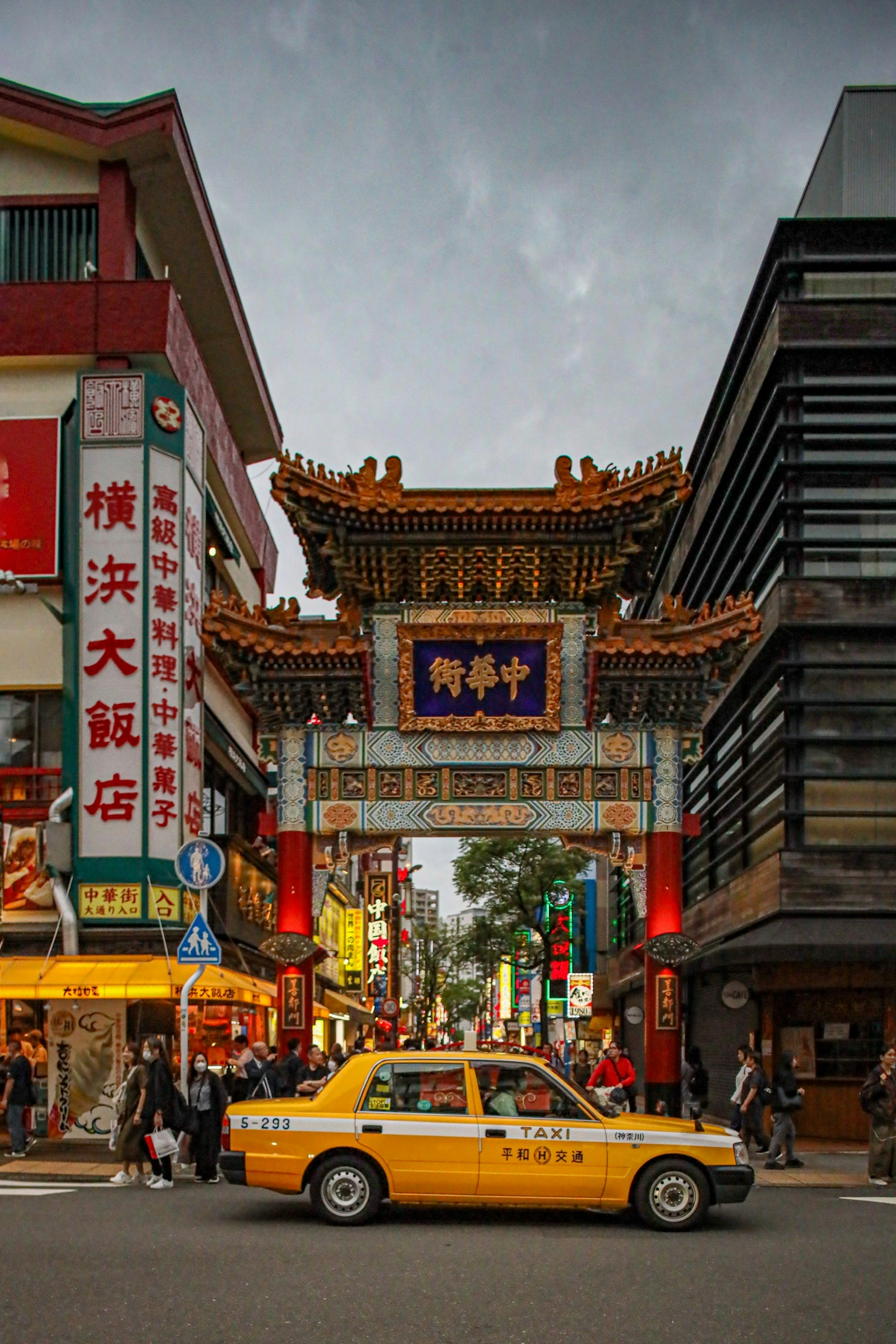 Busy street with a Chinese gate and a taxi in Yokohama Chinatown
