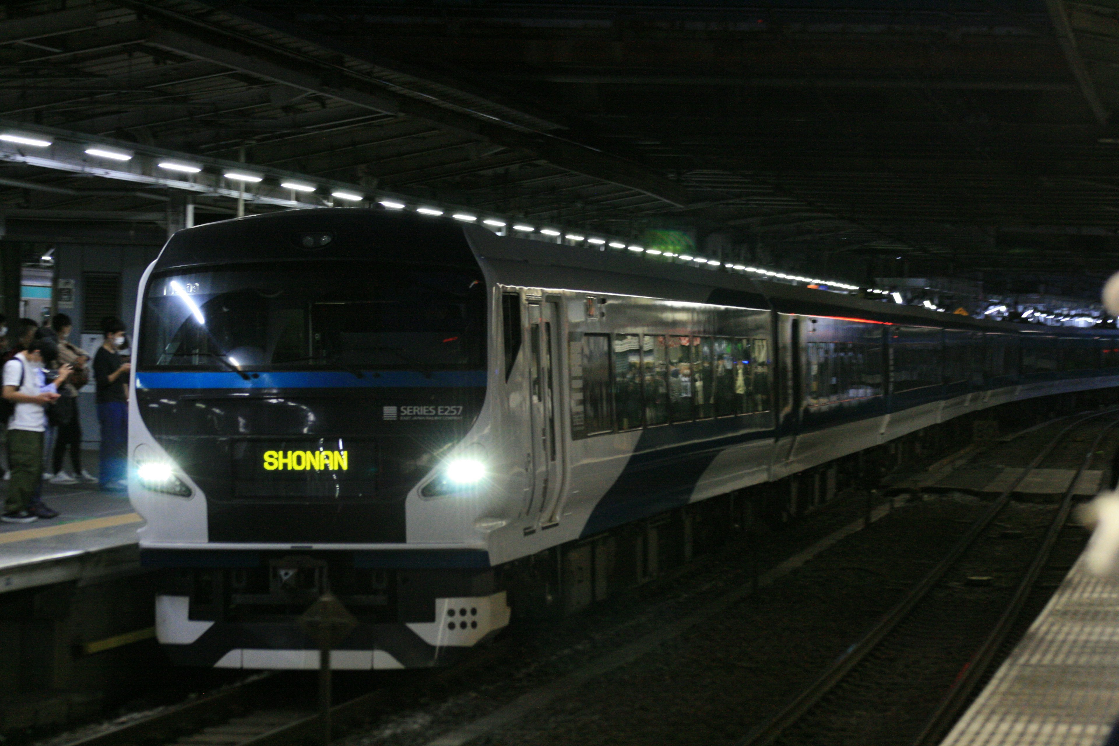 暗い駅で停車中の現代的な列車 鉄道のプラットフォームに乗客が待機