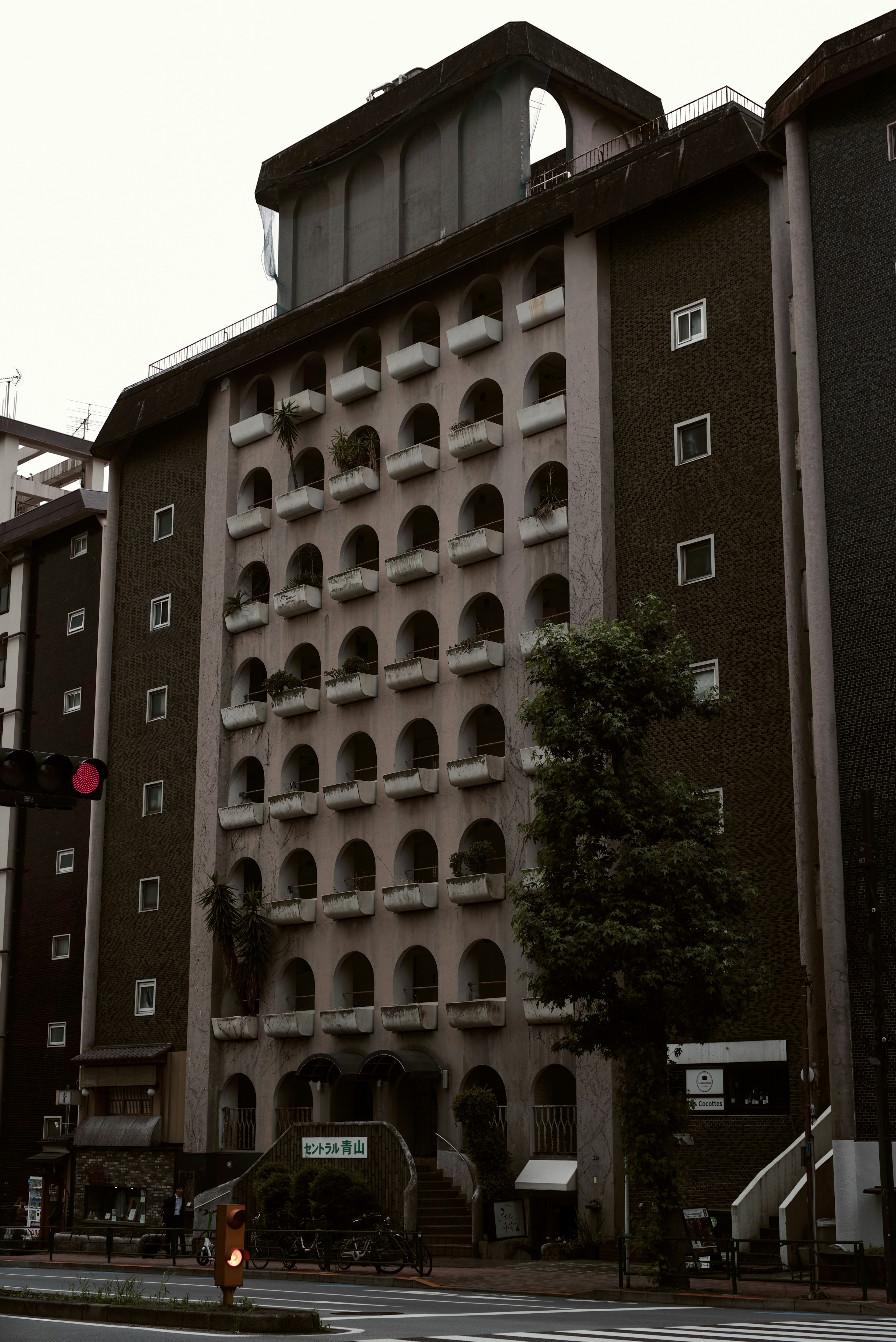 Street view of an old building with arched windows and greenery
