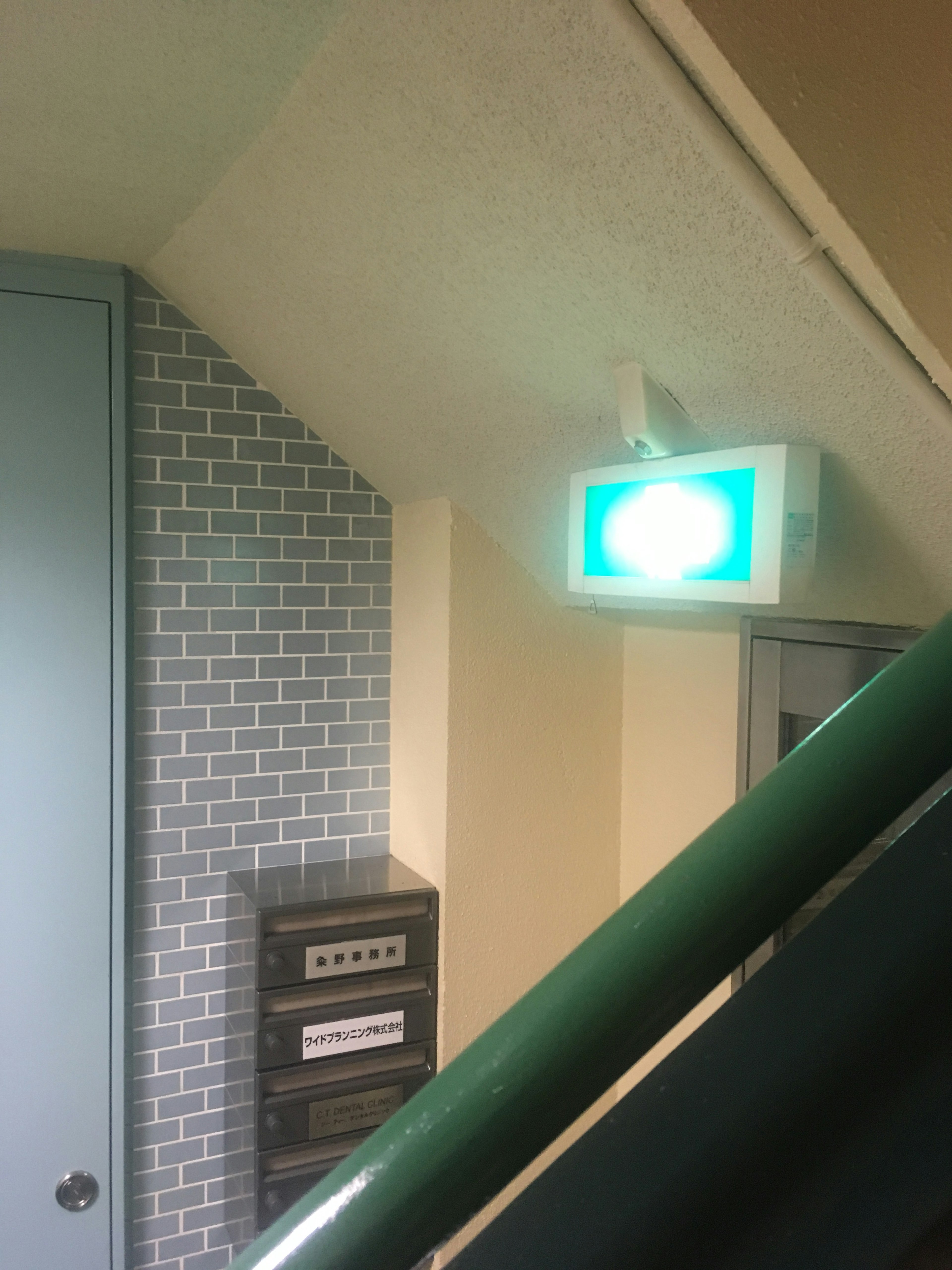 Panneau de sortie de secours vert dans un coin d'escalier avec un mur en brique