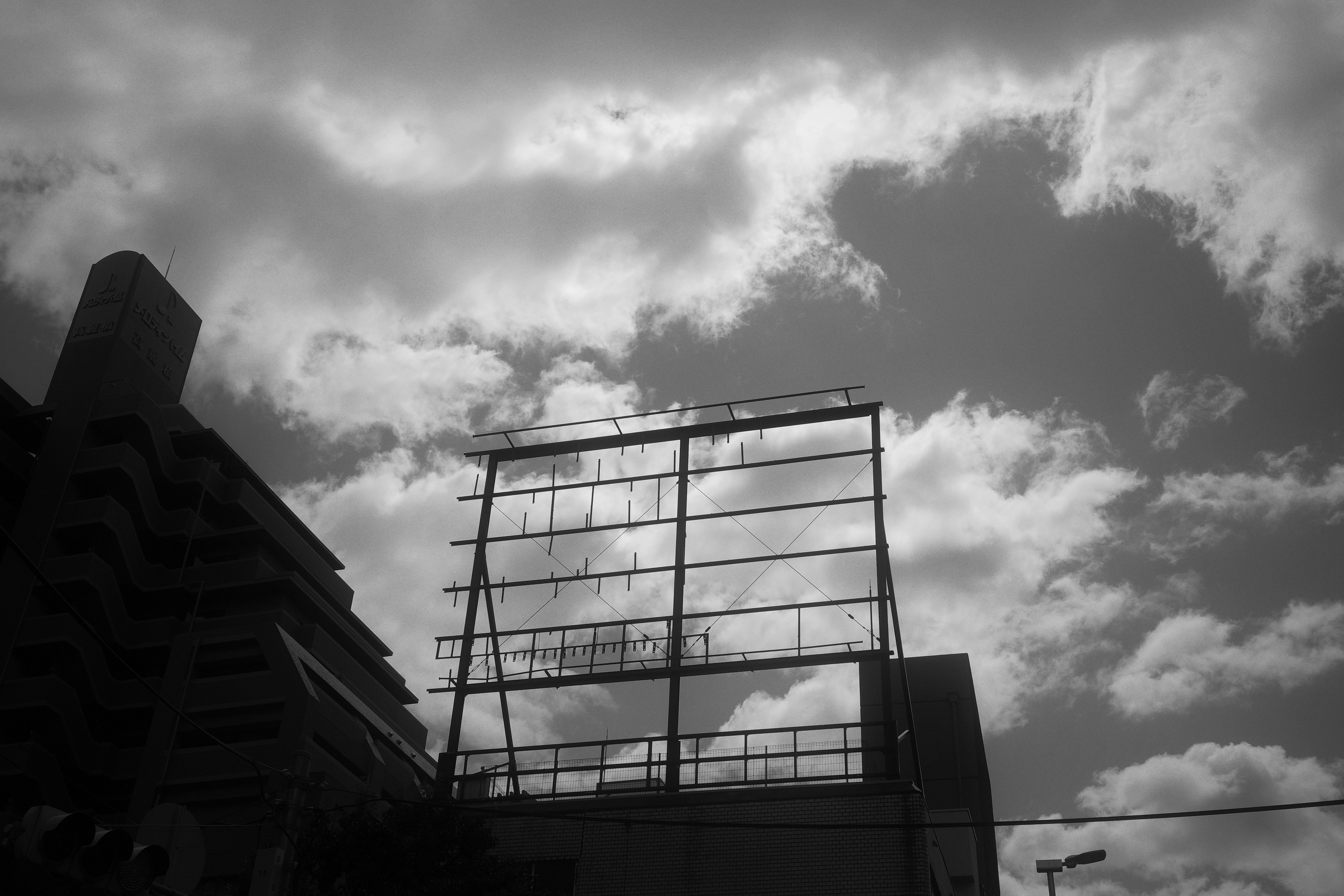 Black and white image featuring a building and cloudy sky