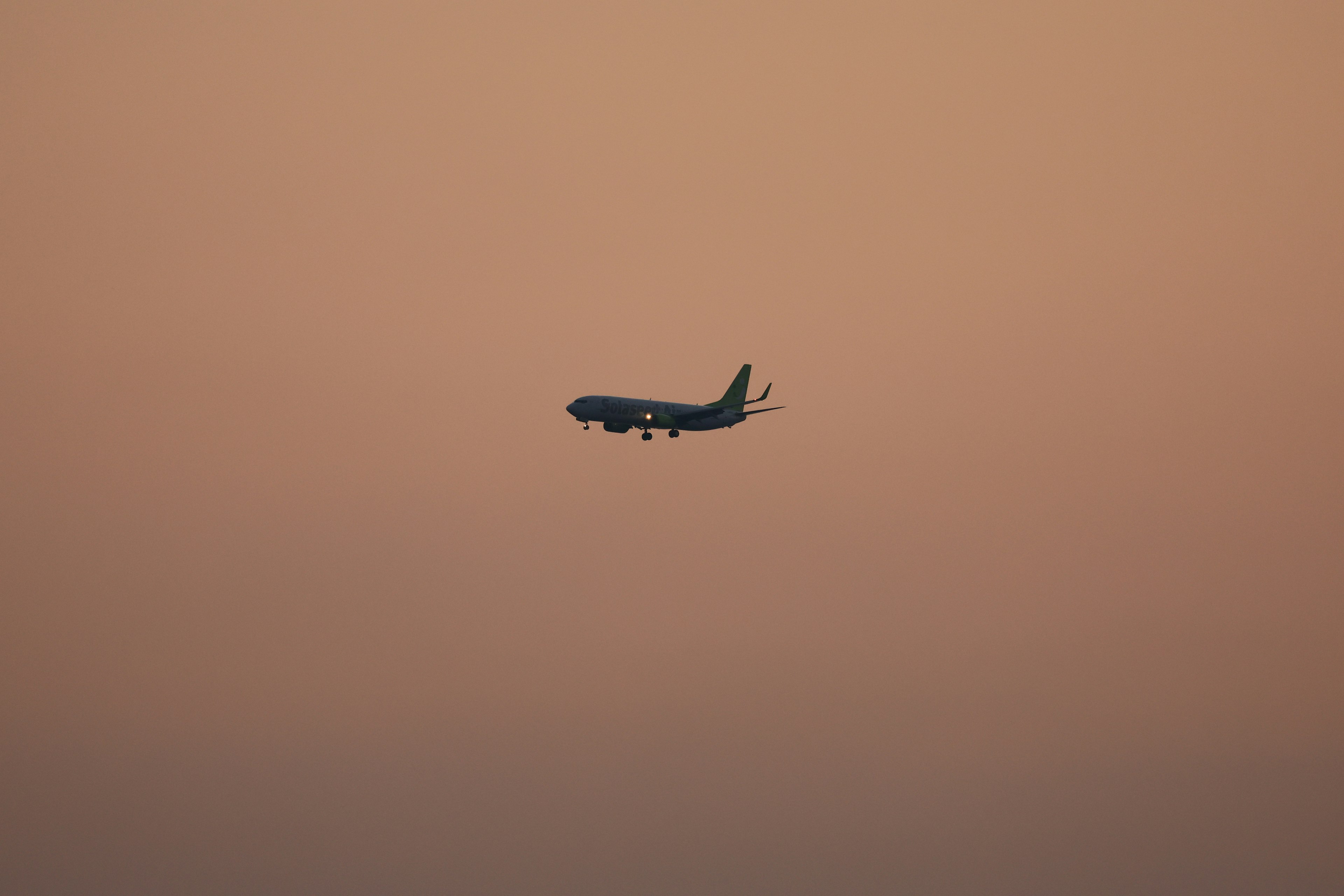 Silhouette of an airplane flying in a sunset sky