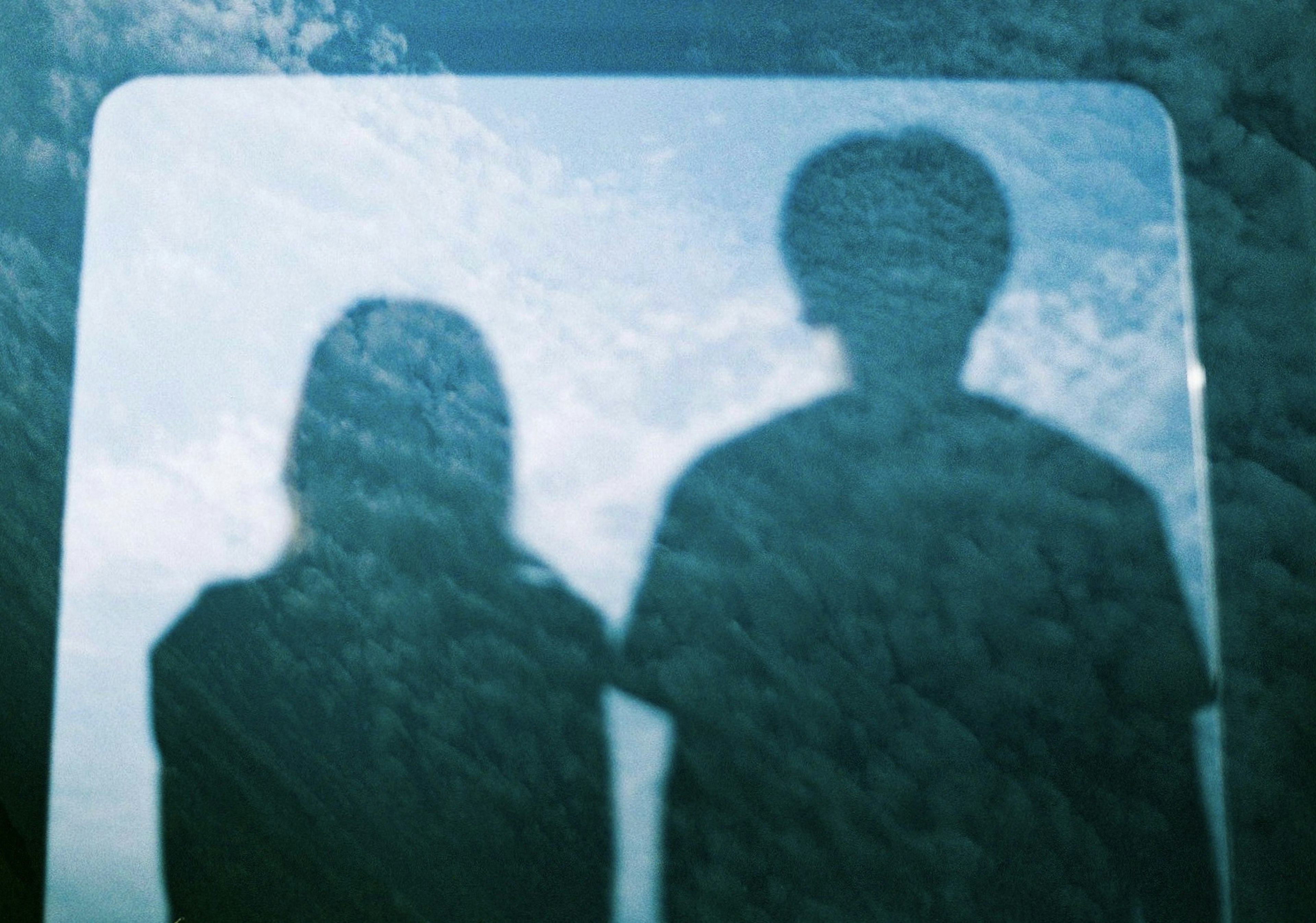 Silhouettes of two people against a cloudy sky