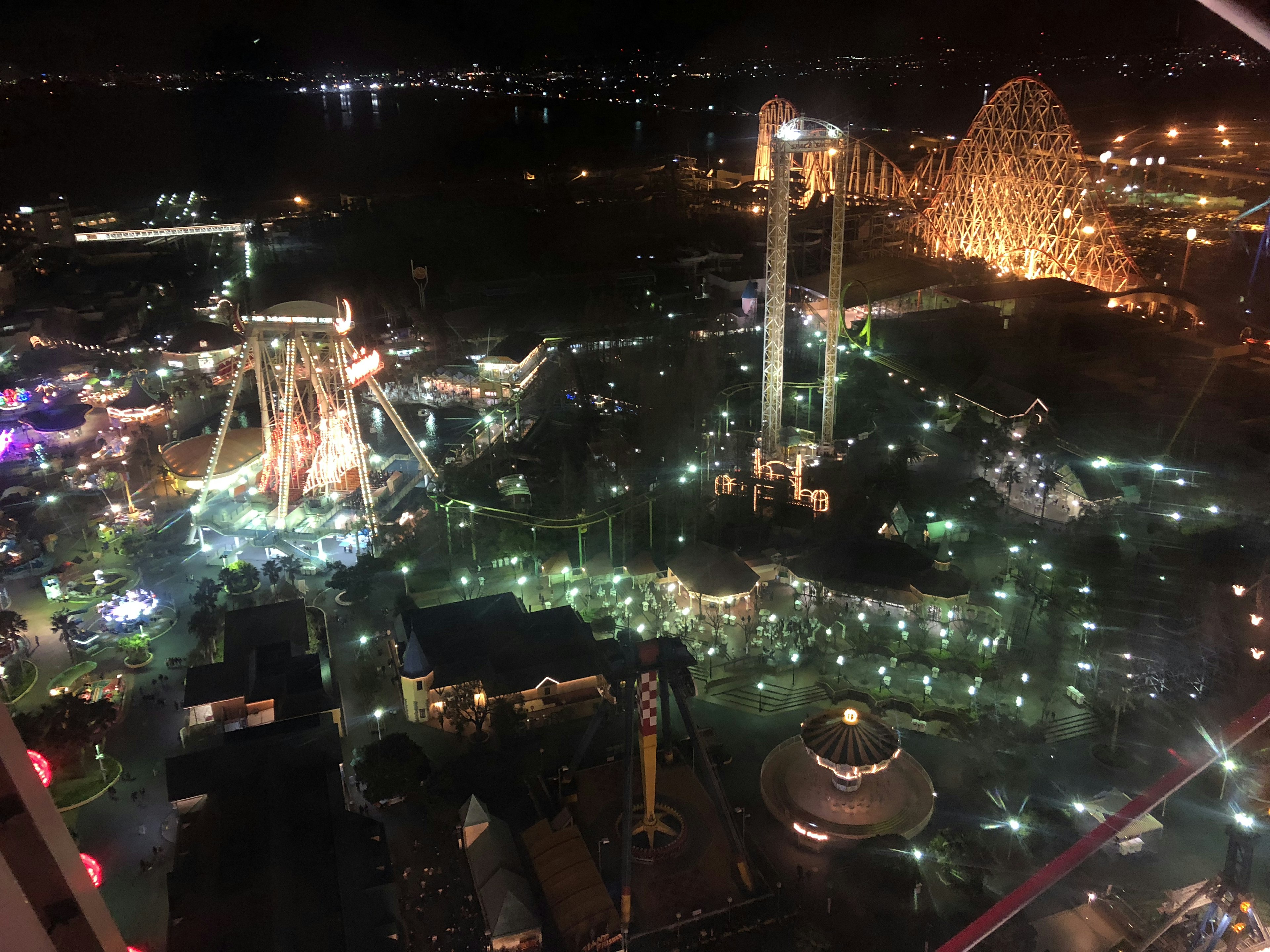 Aerial view of an amusement park at night featuring colorful lights and attractions