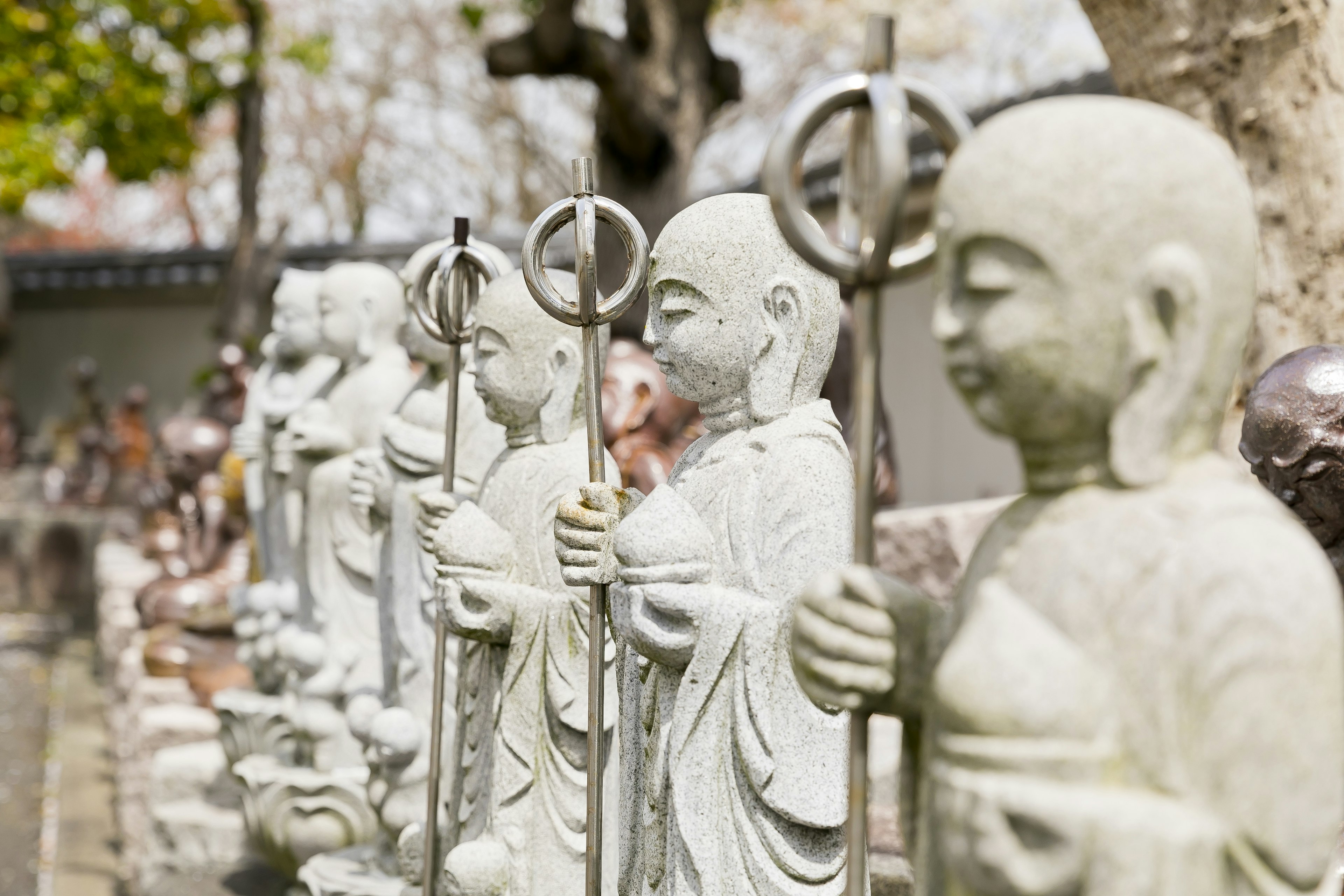 Un paesaggio sereno con una fila di statue di pietra di piccoli monaci con bastoni