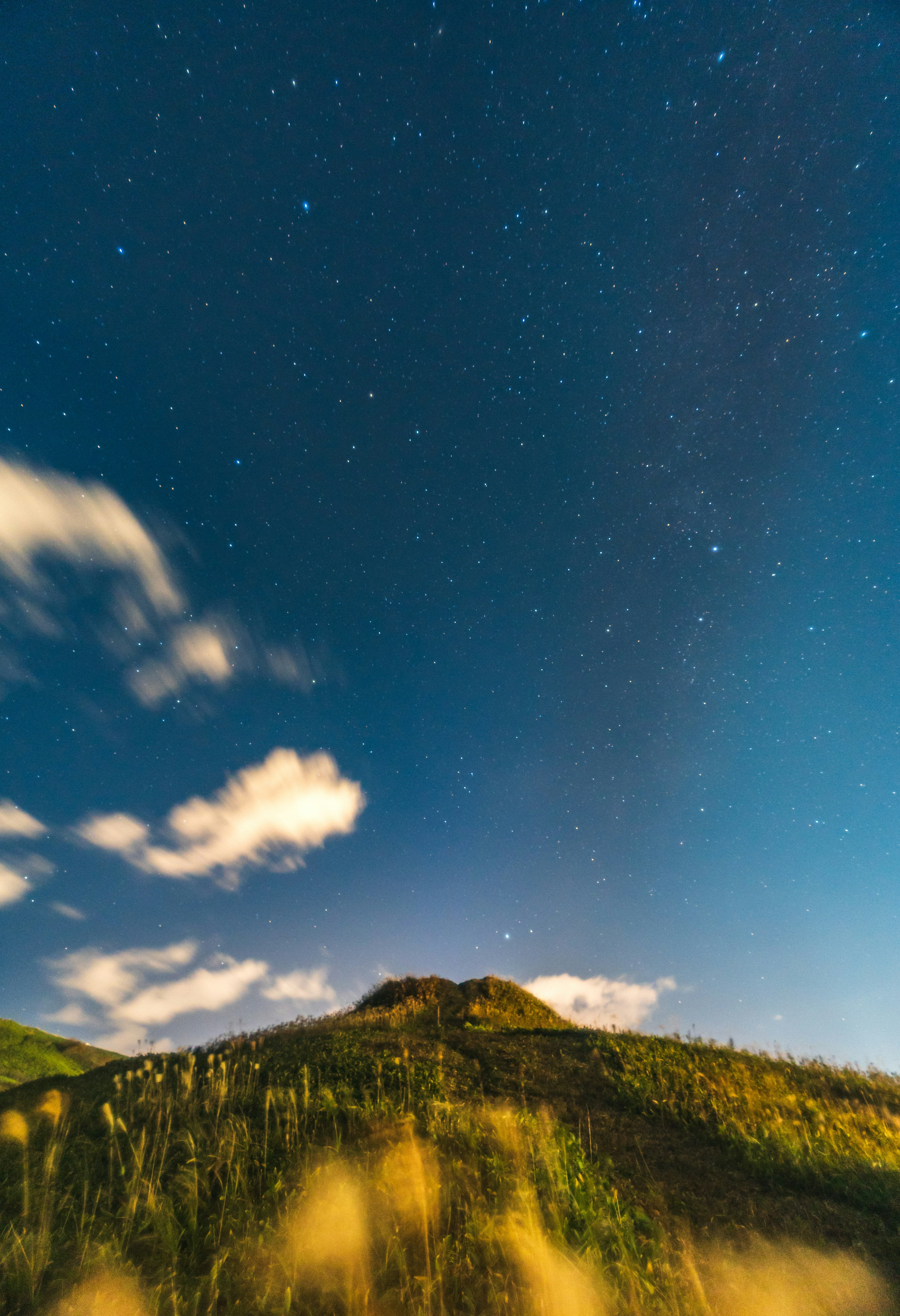 星空の下に広がる緑の丘と雲