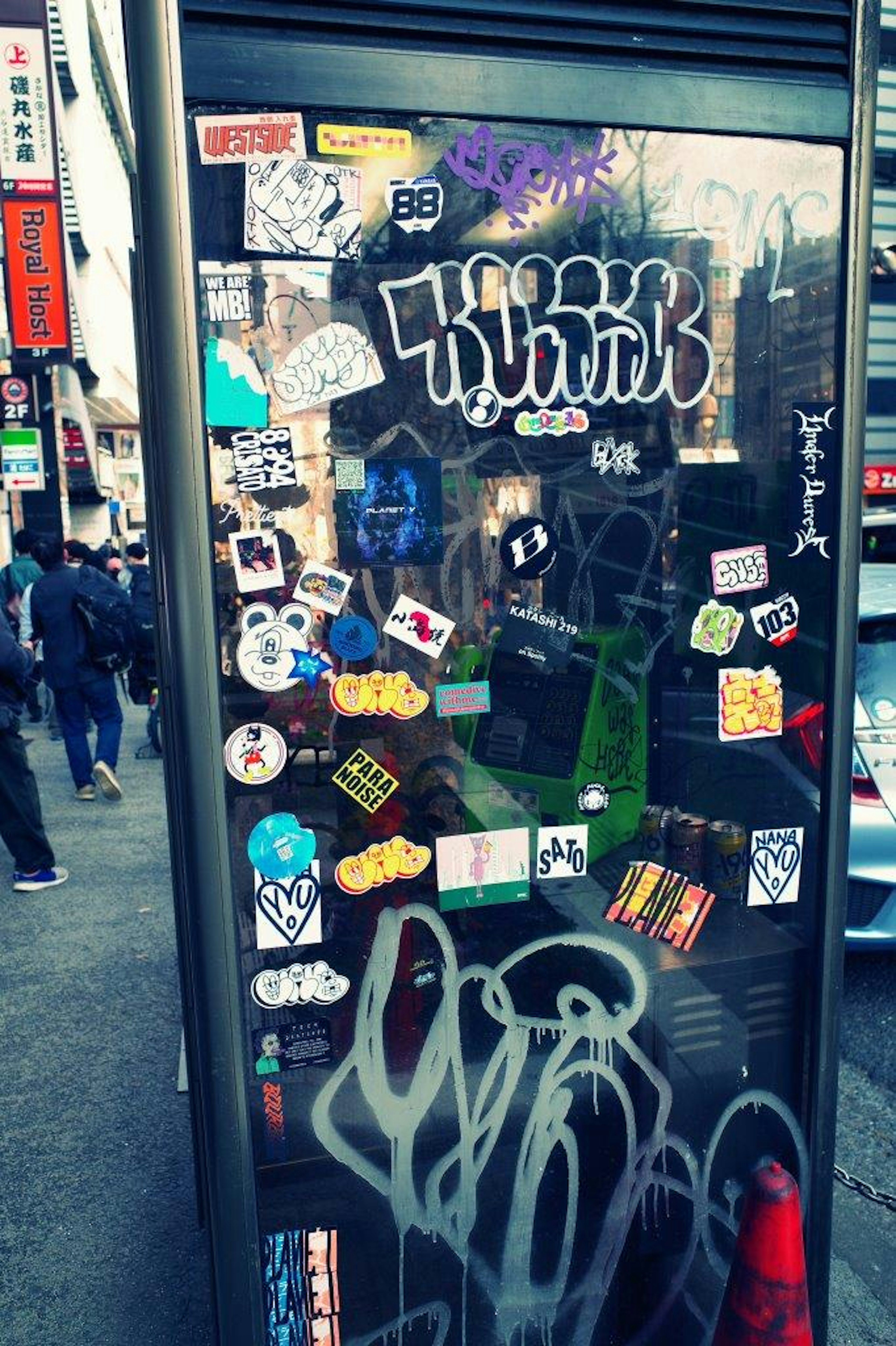 Colorful stickers and graffiti on a phone booth in a busy street