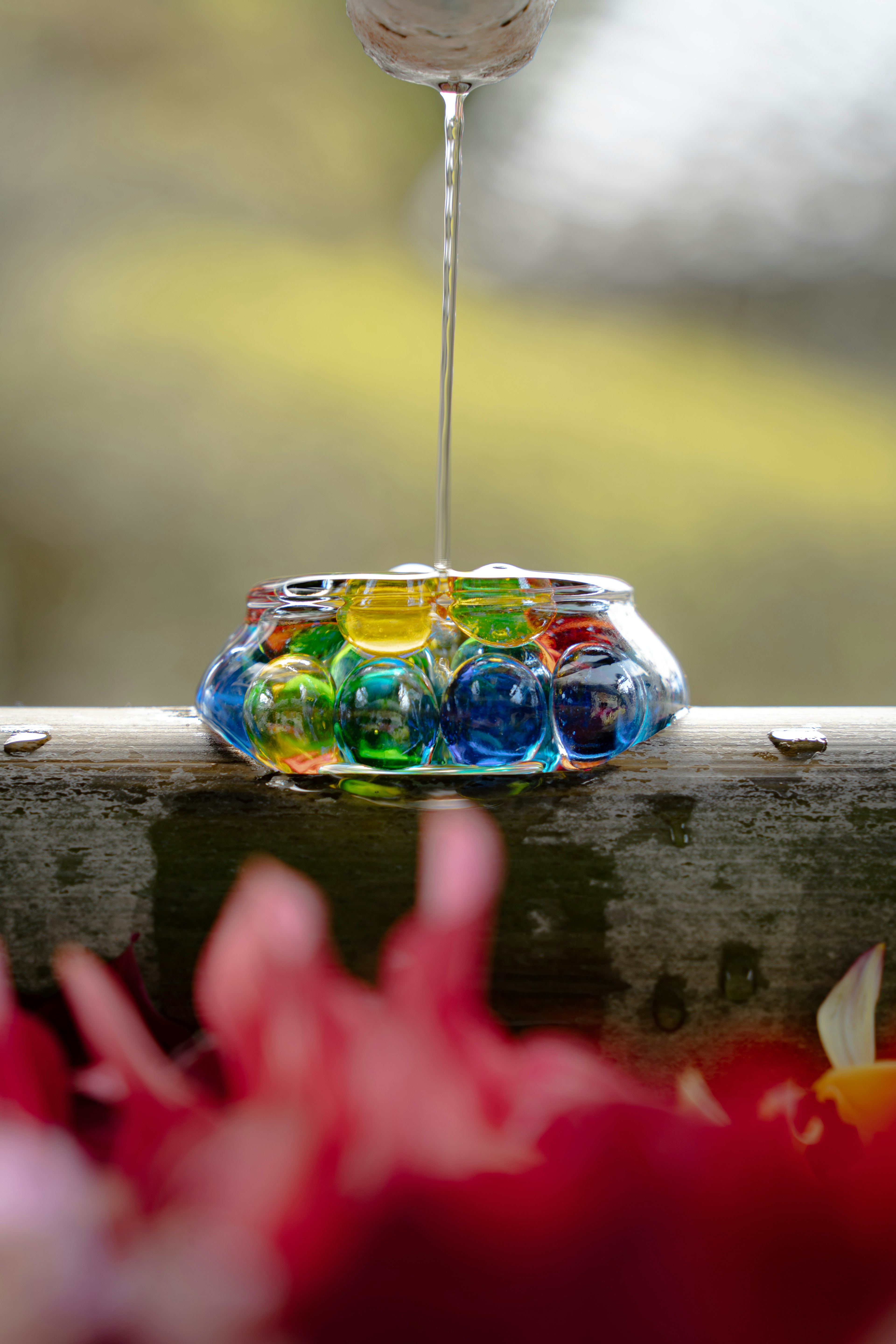 Water pouring into a clear container filled with colorful marbles