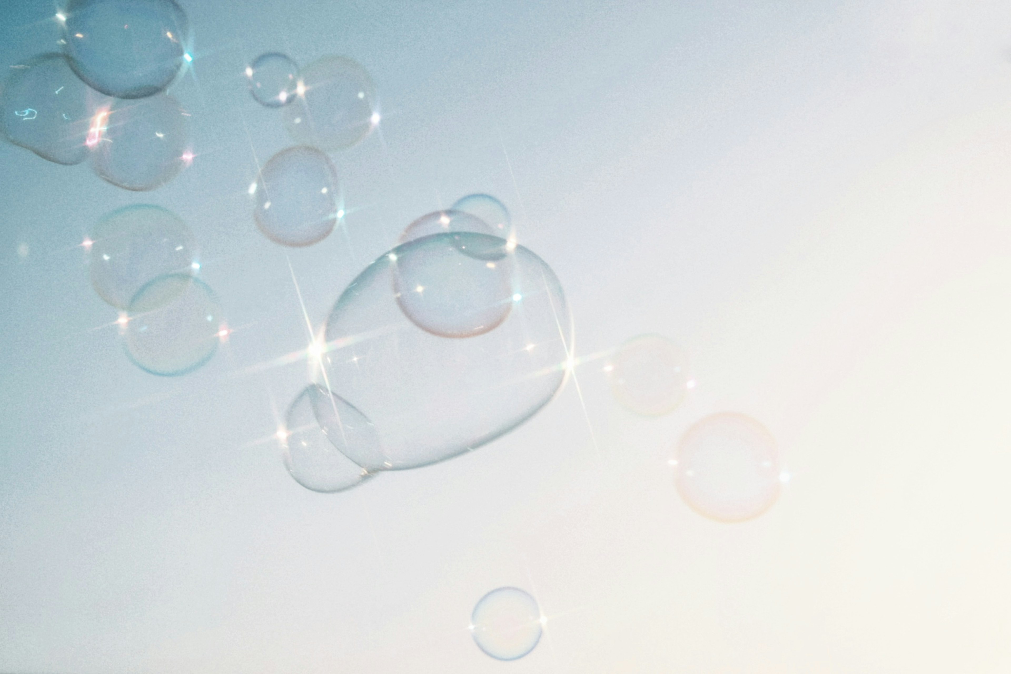 Transparent soap bubbles floating in a blue sky with light reflections