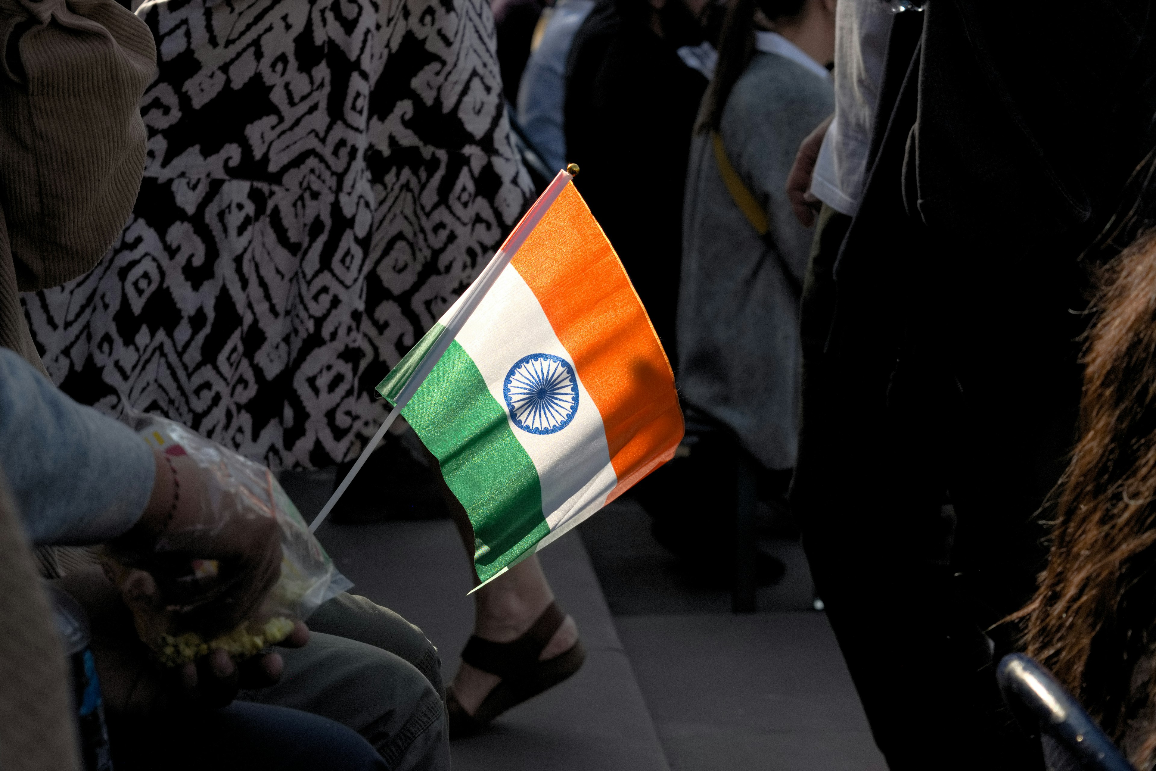 A person holding the Indian flag with people in the background