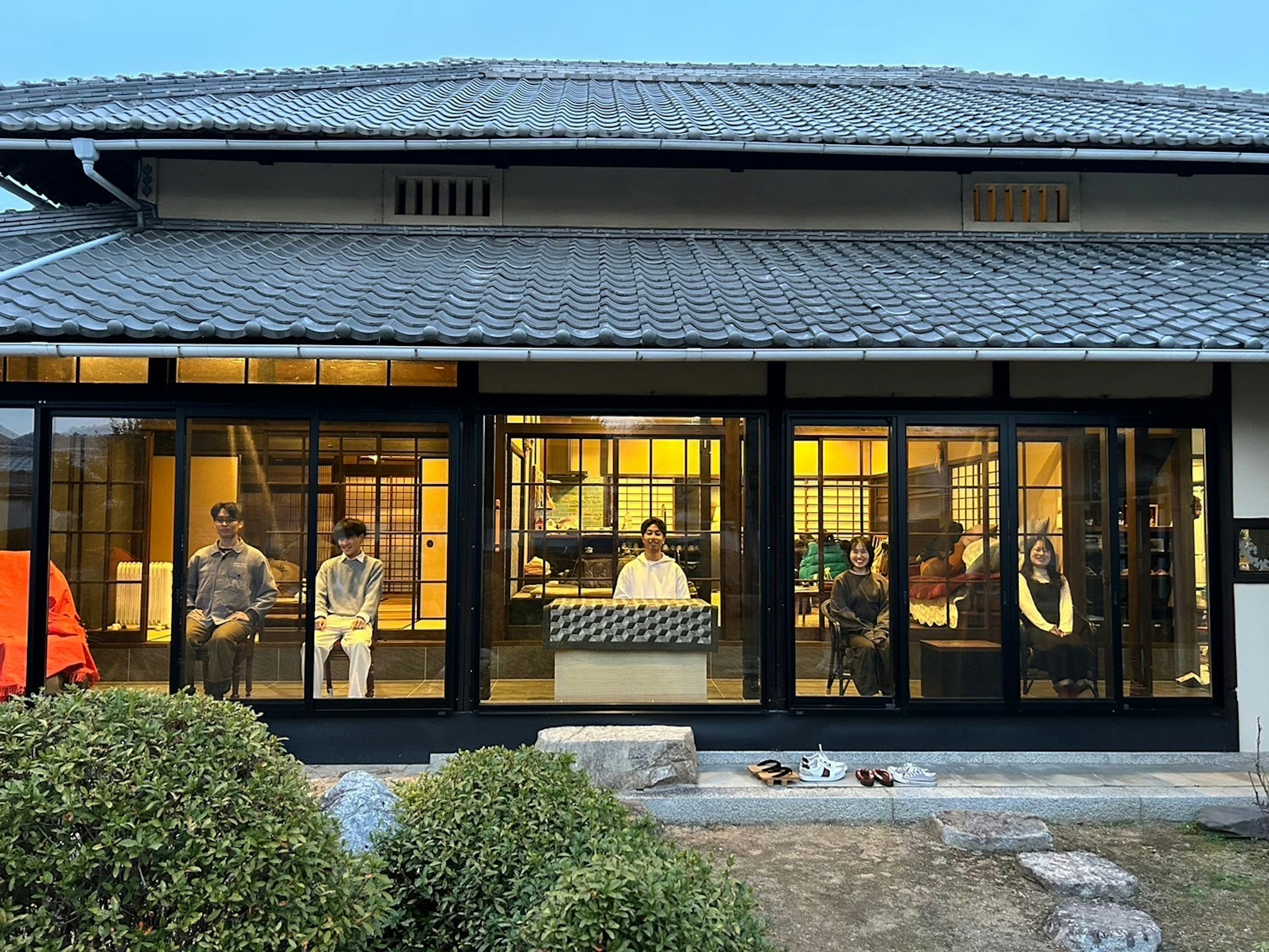 Escena de la tarde mostrando personas sentadas dentro de una casa japonesa tradicional