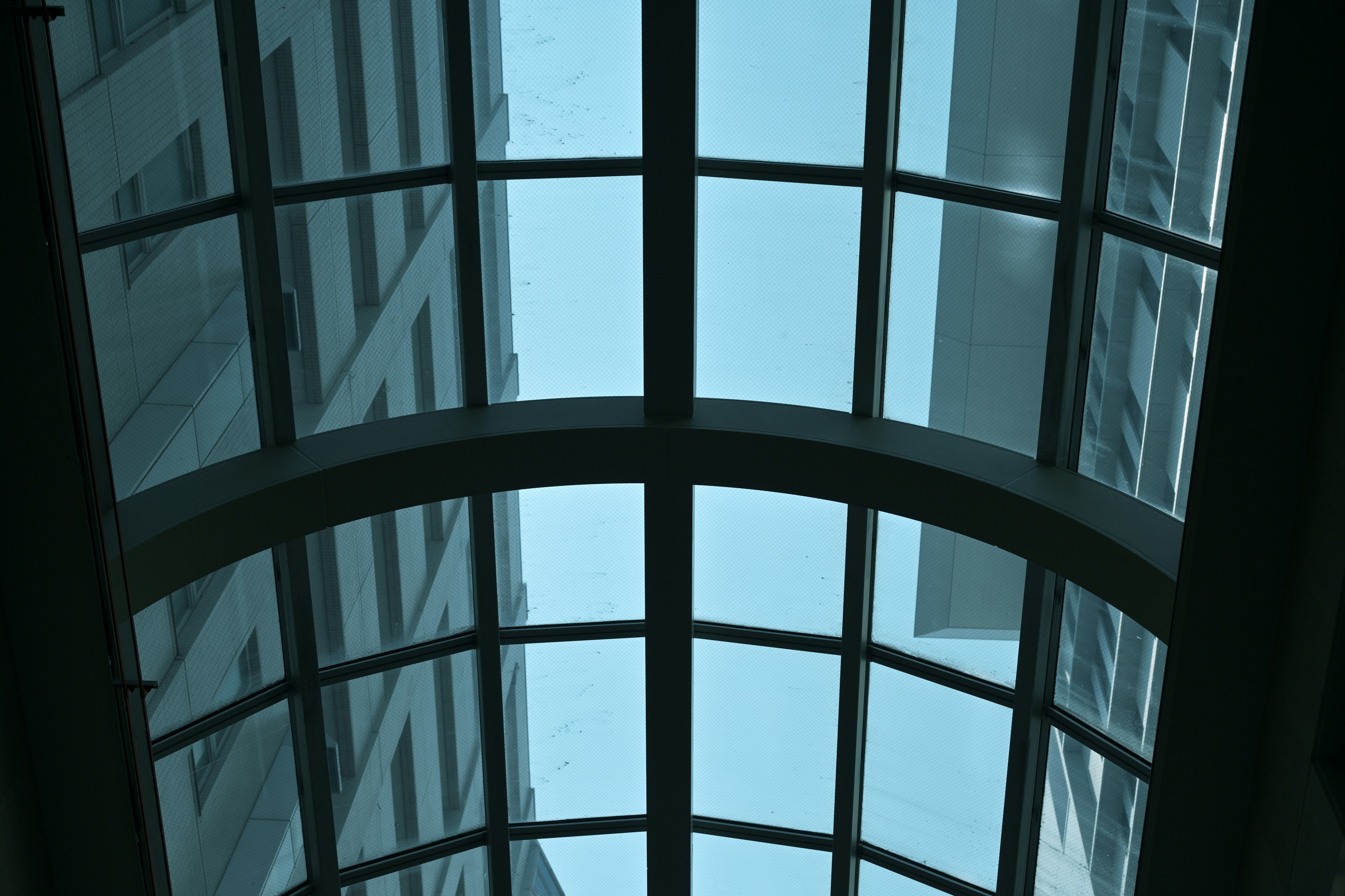 Arched glass ceiling structure with blue sky background