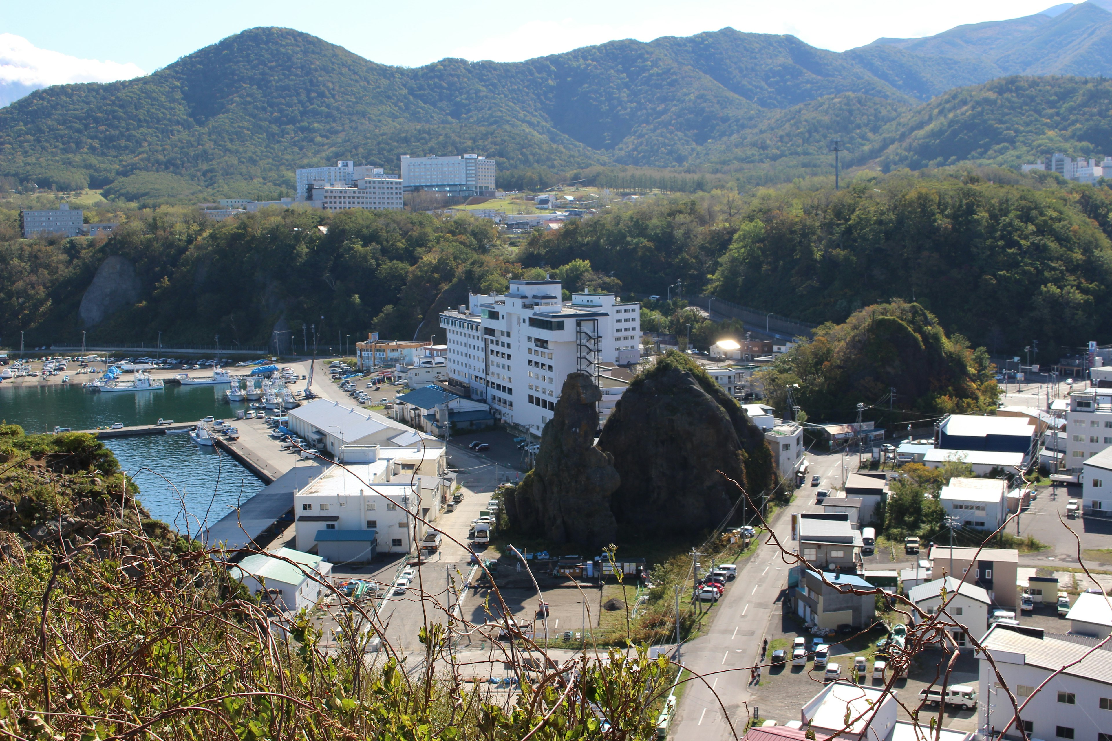 Vue panoramique d'une ville côtière entourée de montagnes avec de gros rochers et des bâtiments