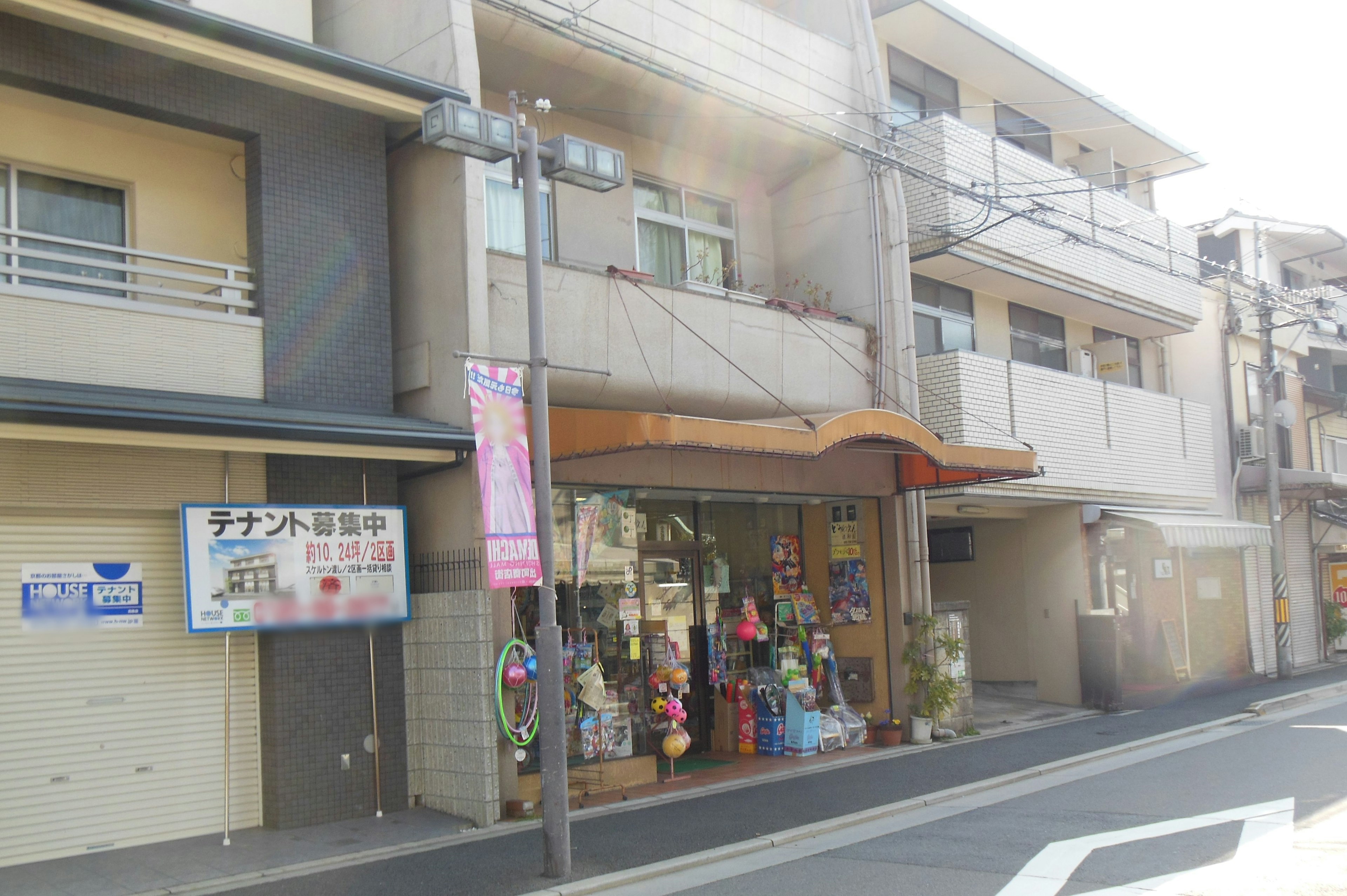 Street view featuring a small shop with a variety of items displayed in the window