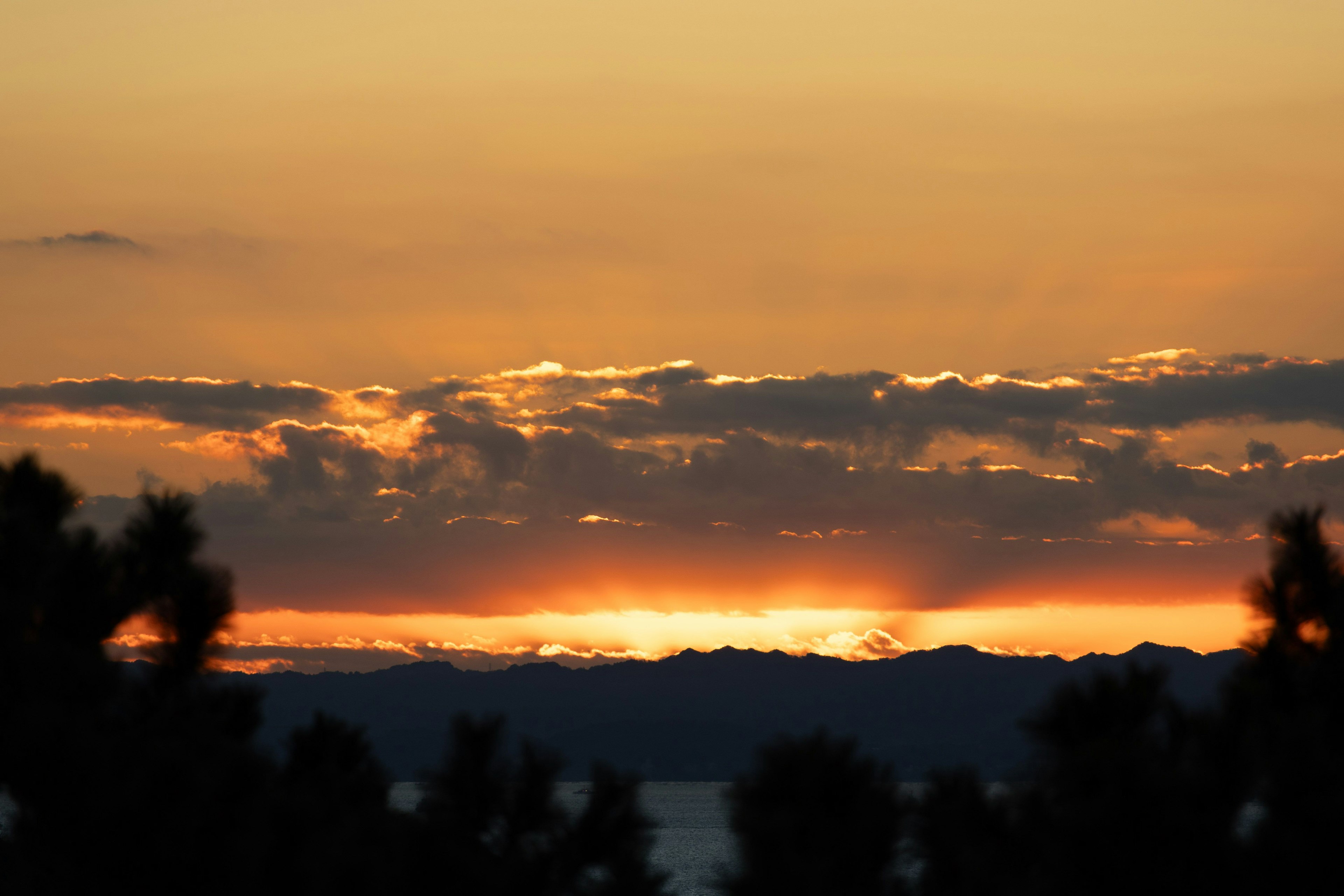 夕焼けの美しい風景 山々のシルエットとオレンジ色の空
